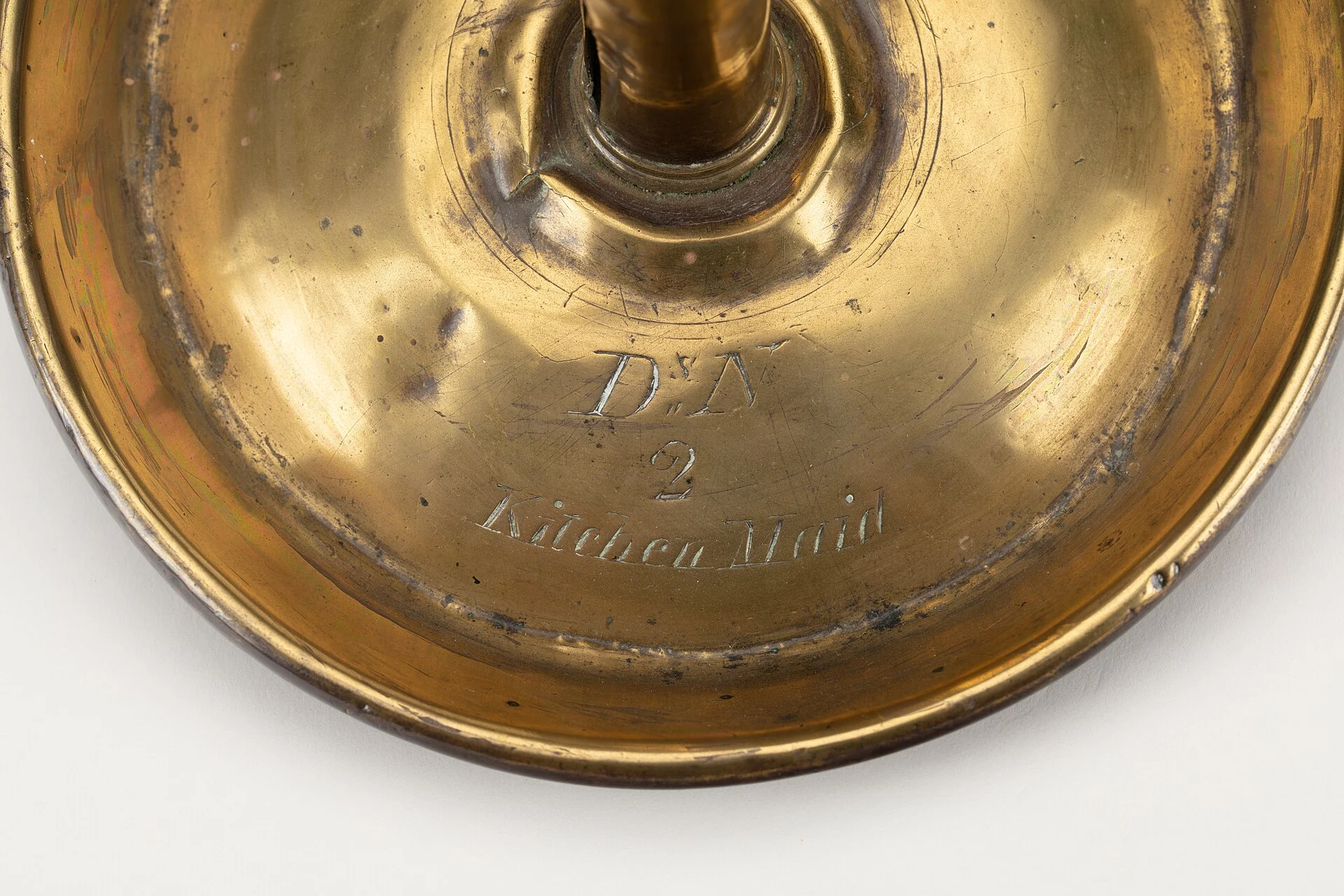 Close view of a worn brass candlestick dish showing uneven tarnish