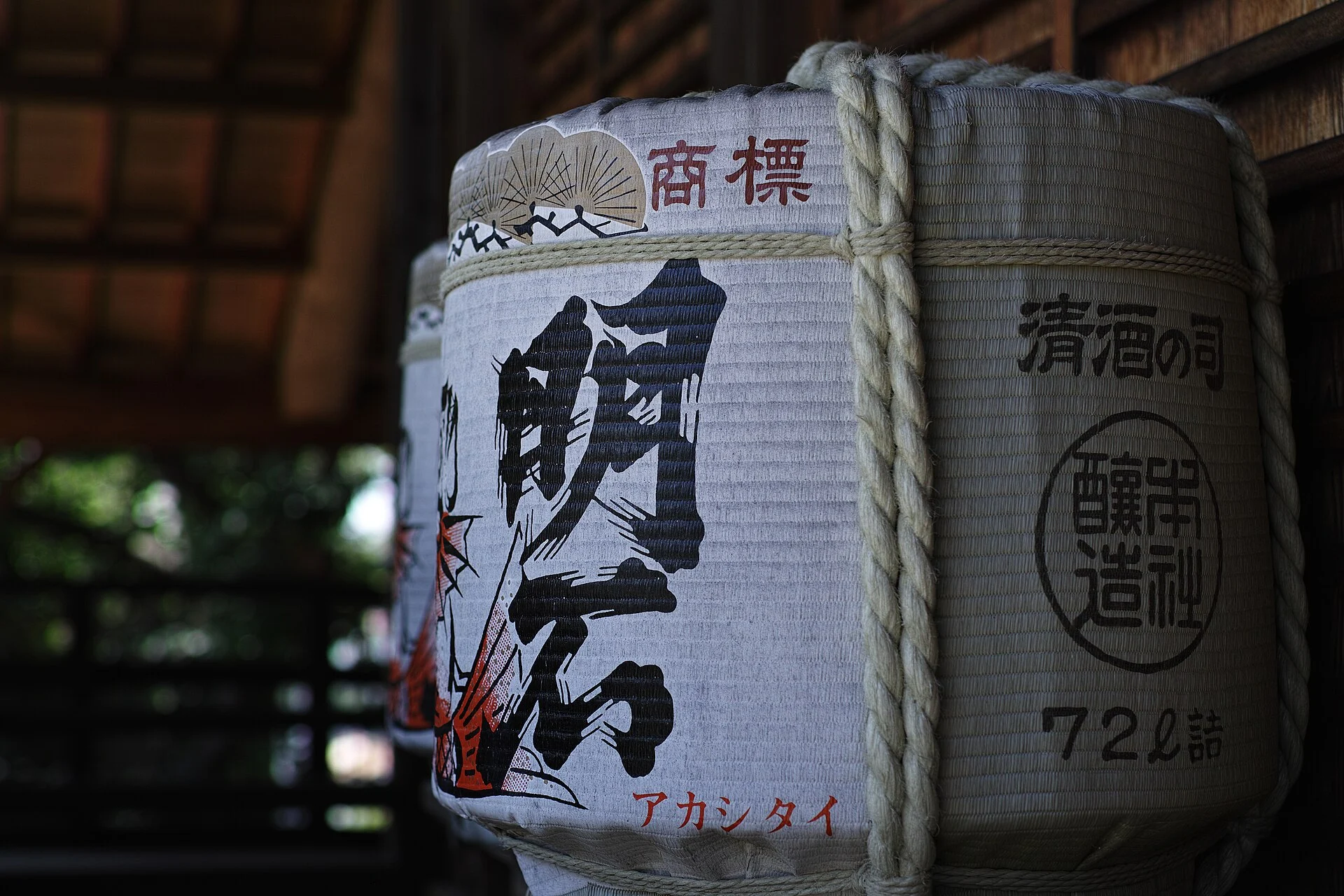 Straw-wrapped sake barrel with a printed brand name and rope binding