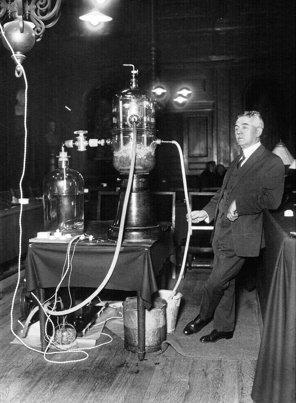 Man in a suit standing beside laboratory apparatus with tall glass vessels