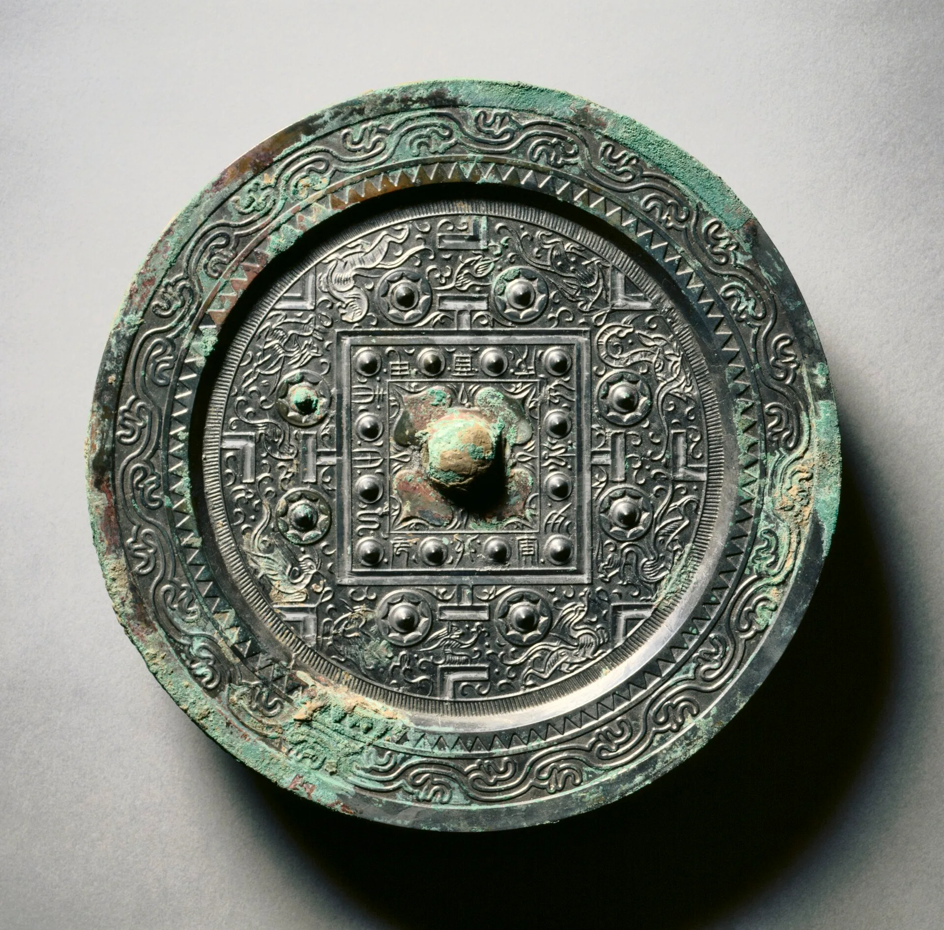 Back of a round bronze Han mirror with a central knob and geometric pattern