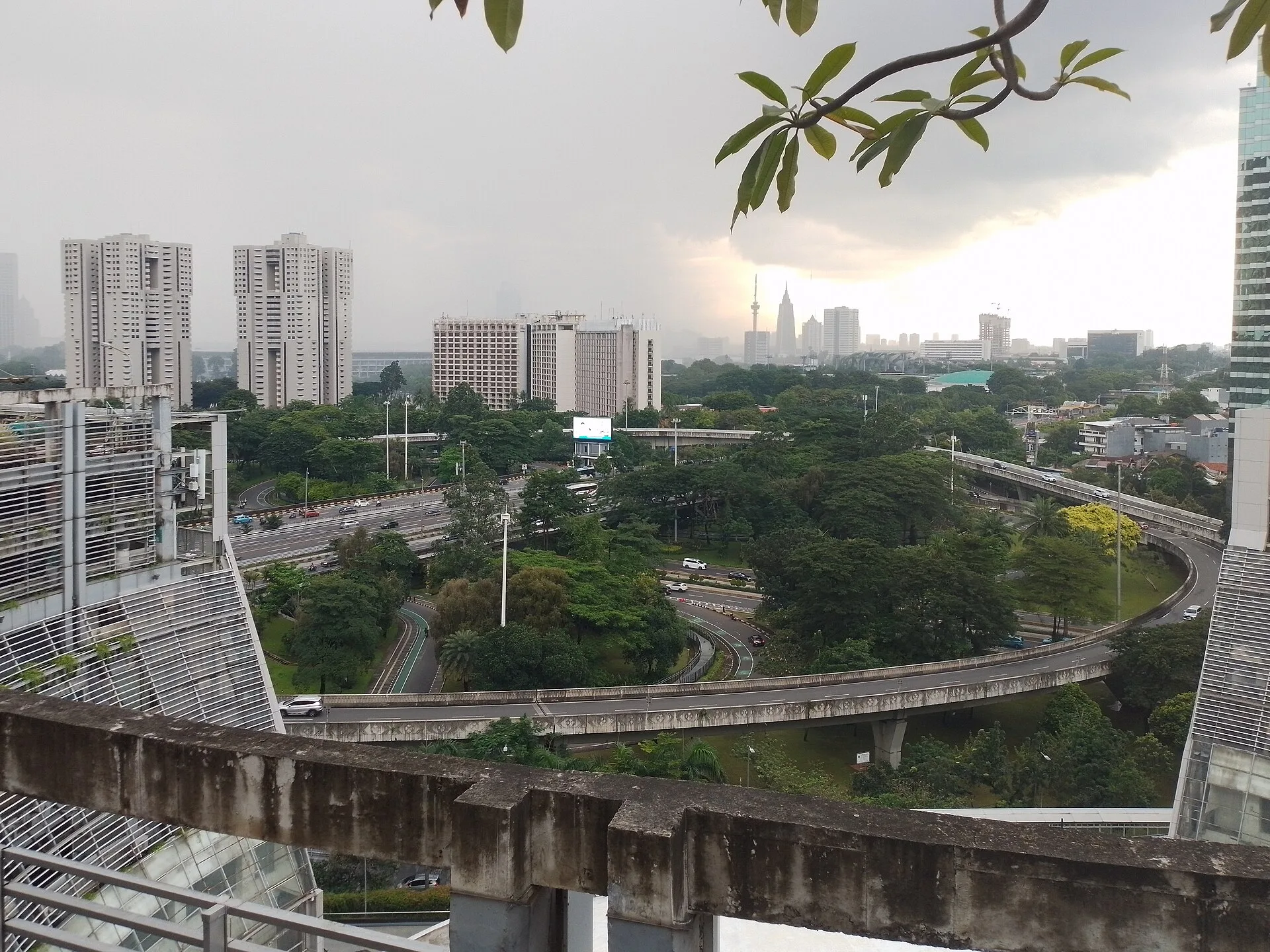 Curved elevated road ramps looping over green space between city buildings