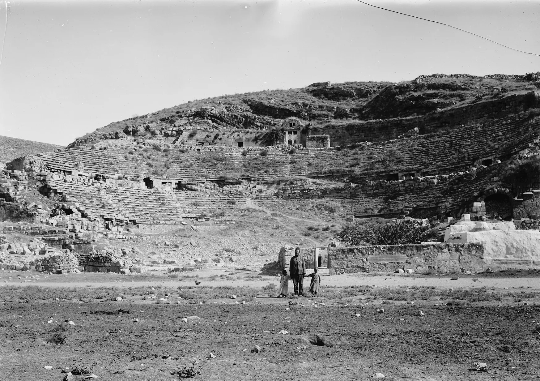 Black and white photograph of ruined theatre seating on a bare hillside