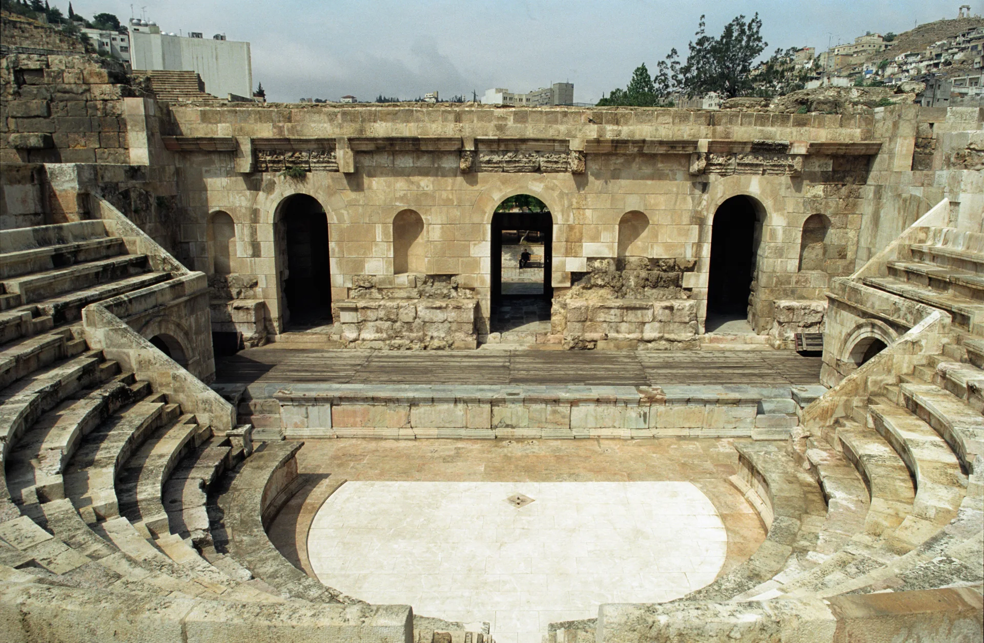 Small semicircular stone odeon with tiered seats and an arched stage wall