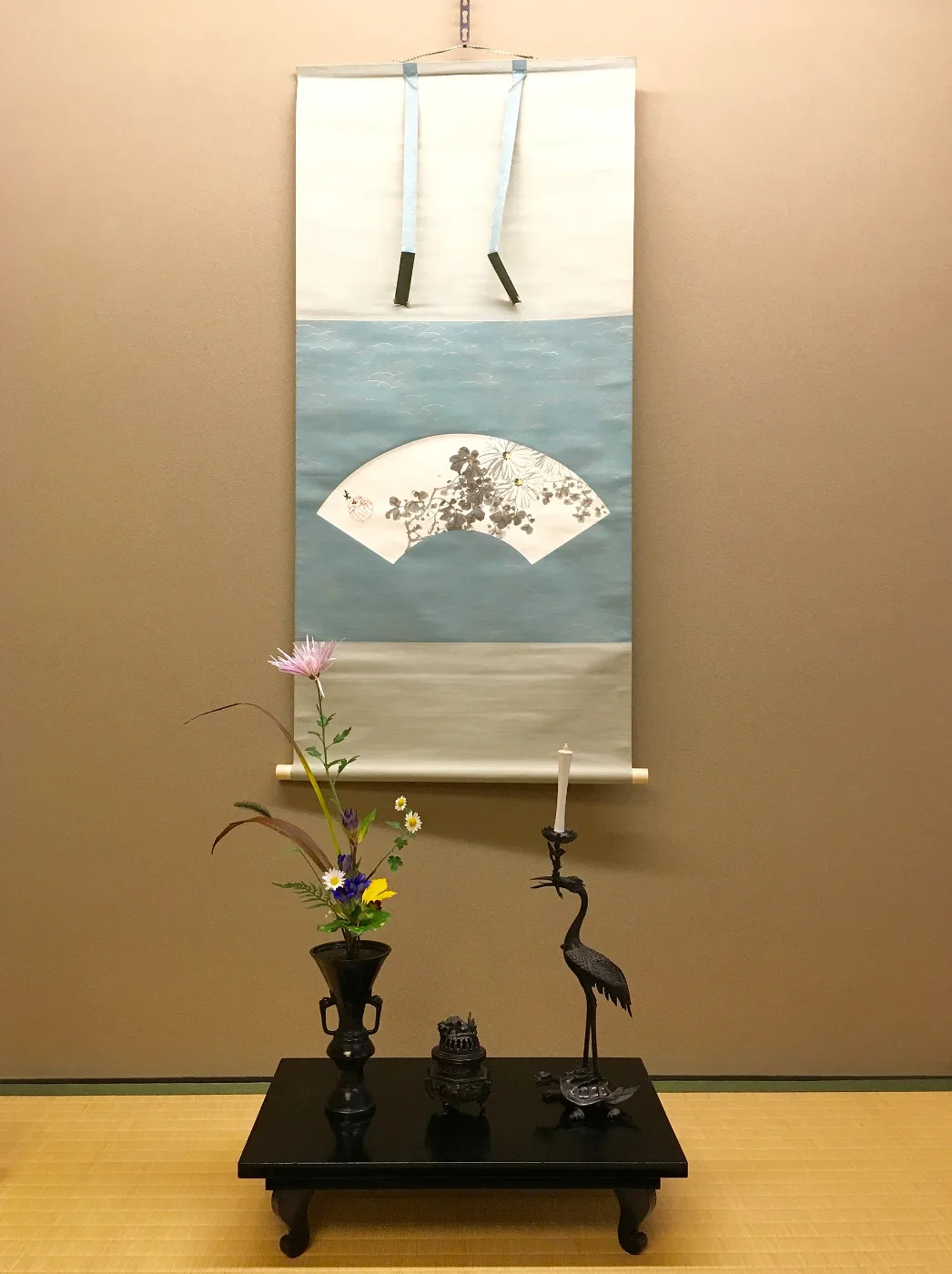 Flower vase and altar objects on a stand below a hanging scroll