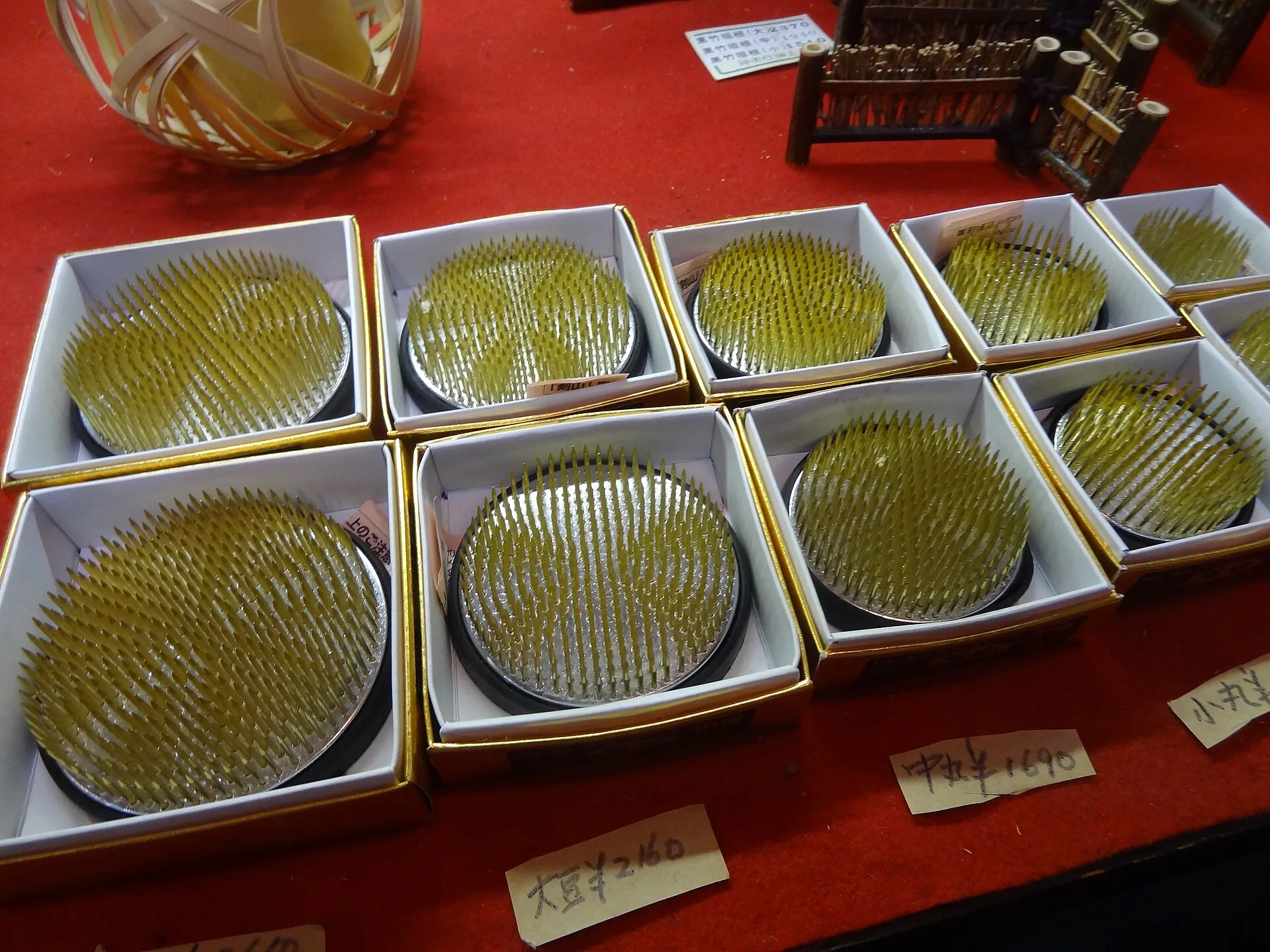 Round metal needle holders arranged in boxes on a shop table