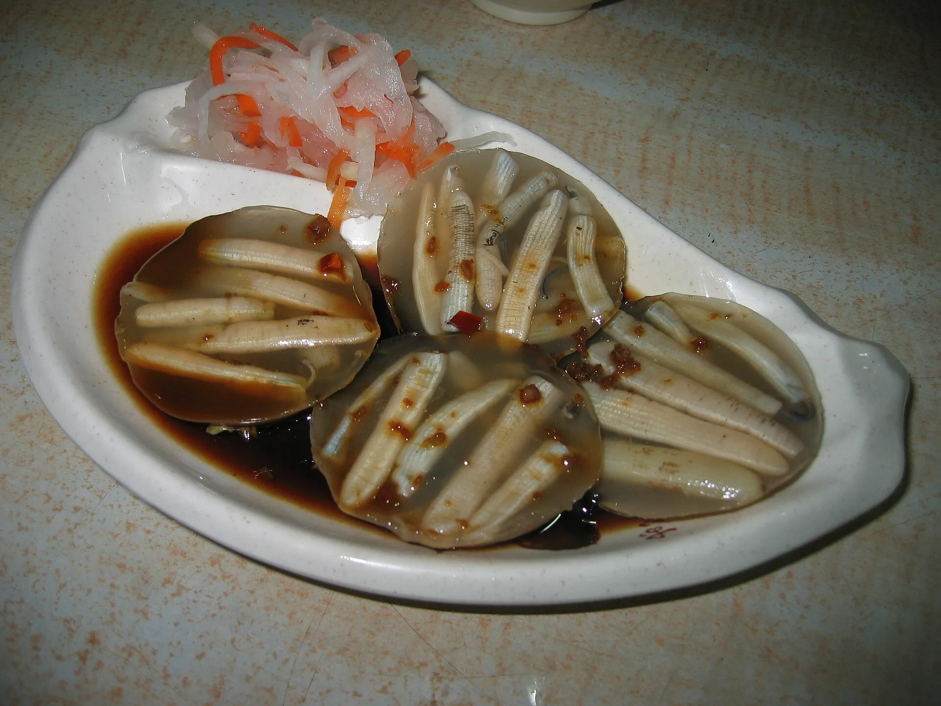 Four round translucent jellies set around pale worms in soy sauce