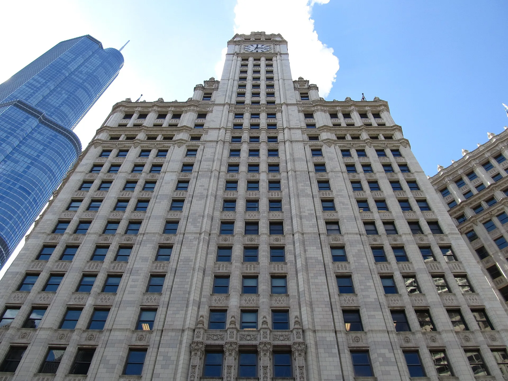 White clad tower of the Wrigley Building seen from street level against blue sky
