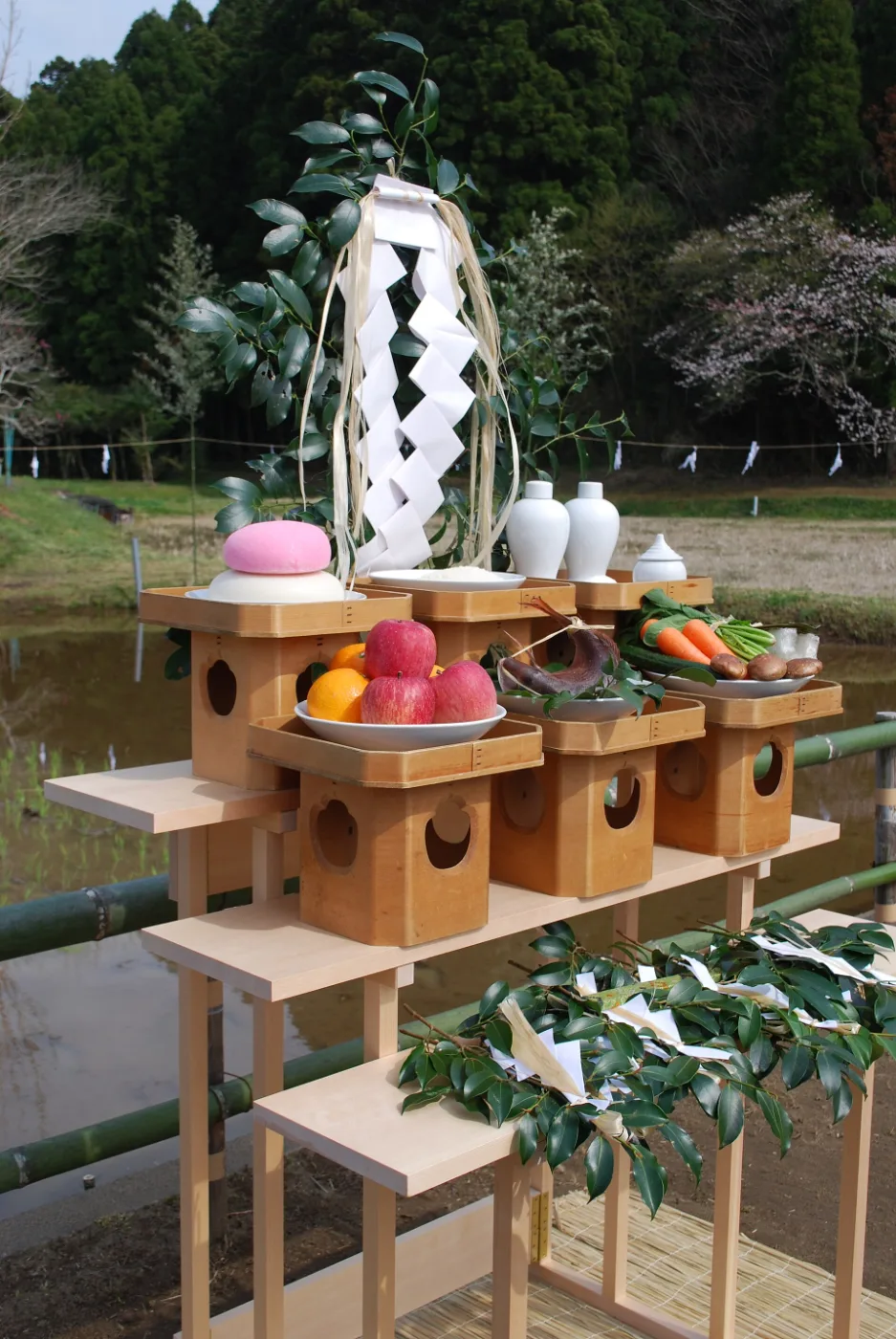 Shrine altar offerings of sake, rice, vegetables, fish and fruit on stands