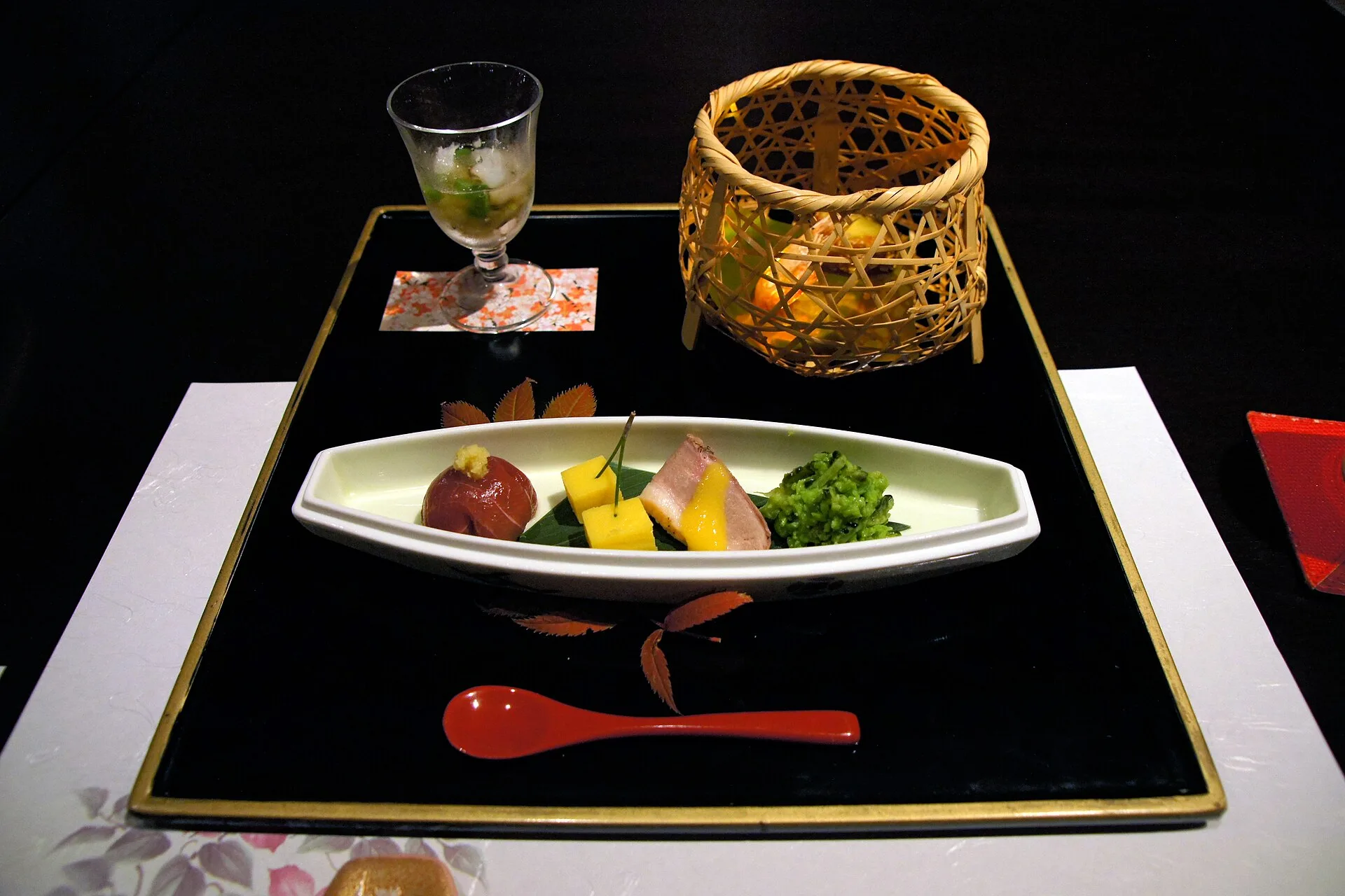 Small seasonal dishes arranged on a long plate on a black lacquer tray