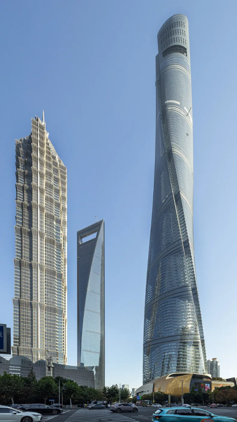 Three supertall glass towers rising together against a blue sky