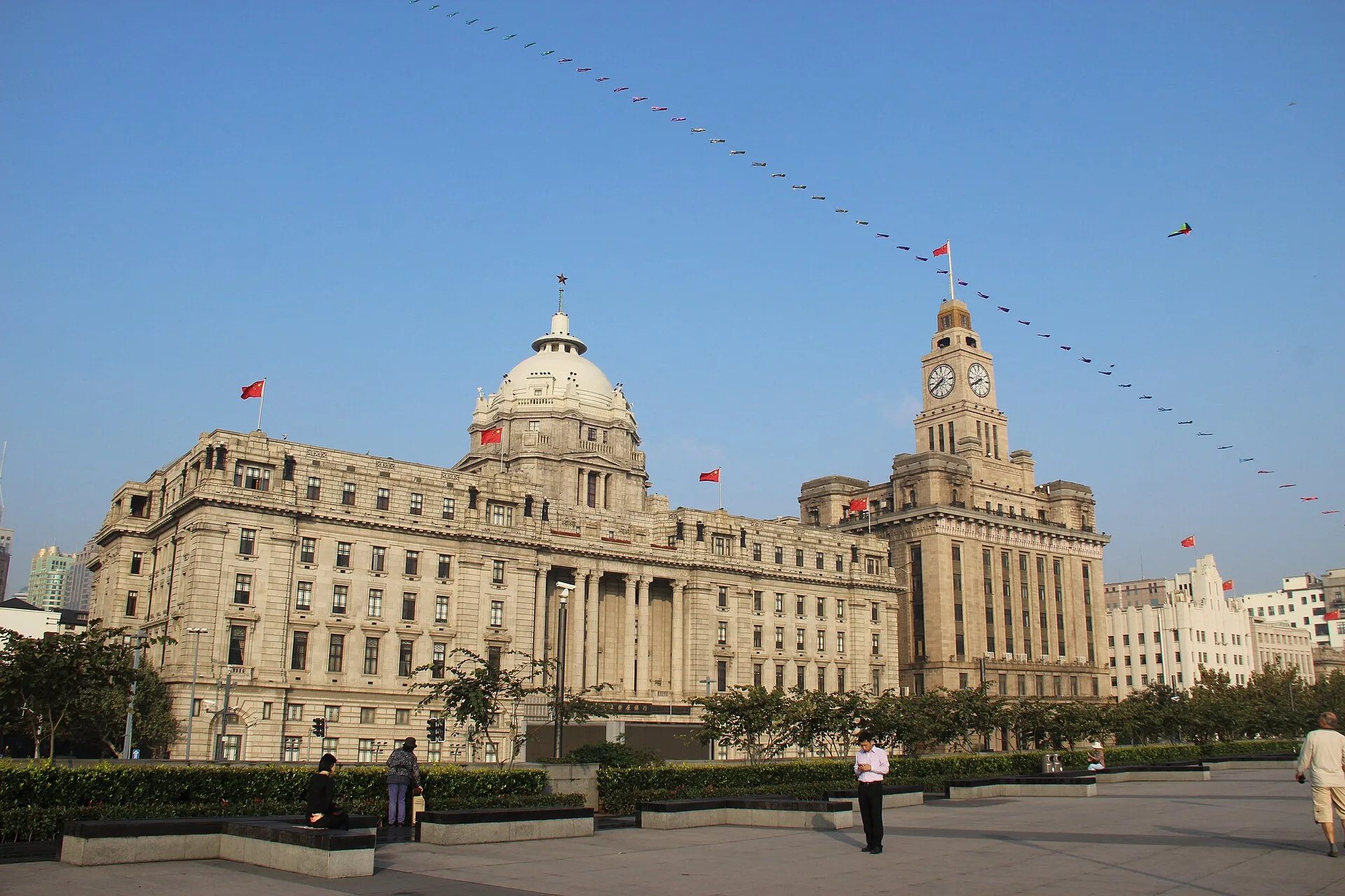 Domed stone bank building beside a tall clock tower building on the Bund