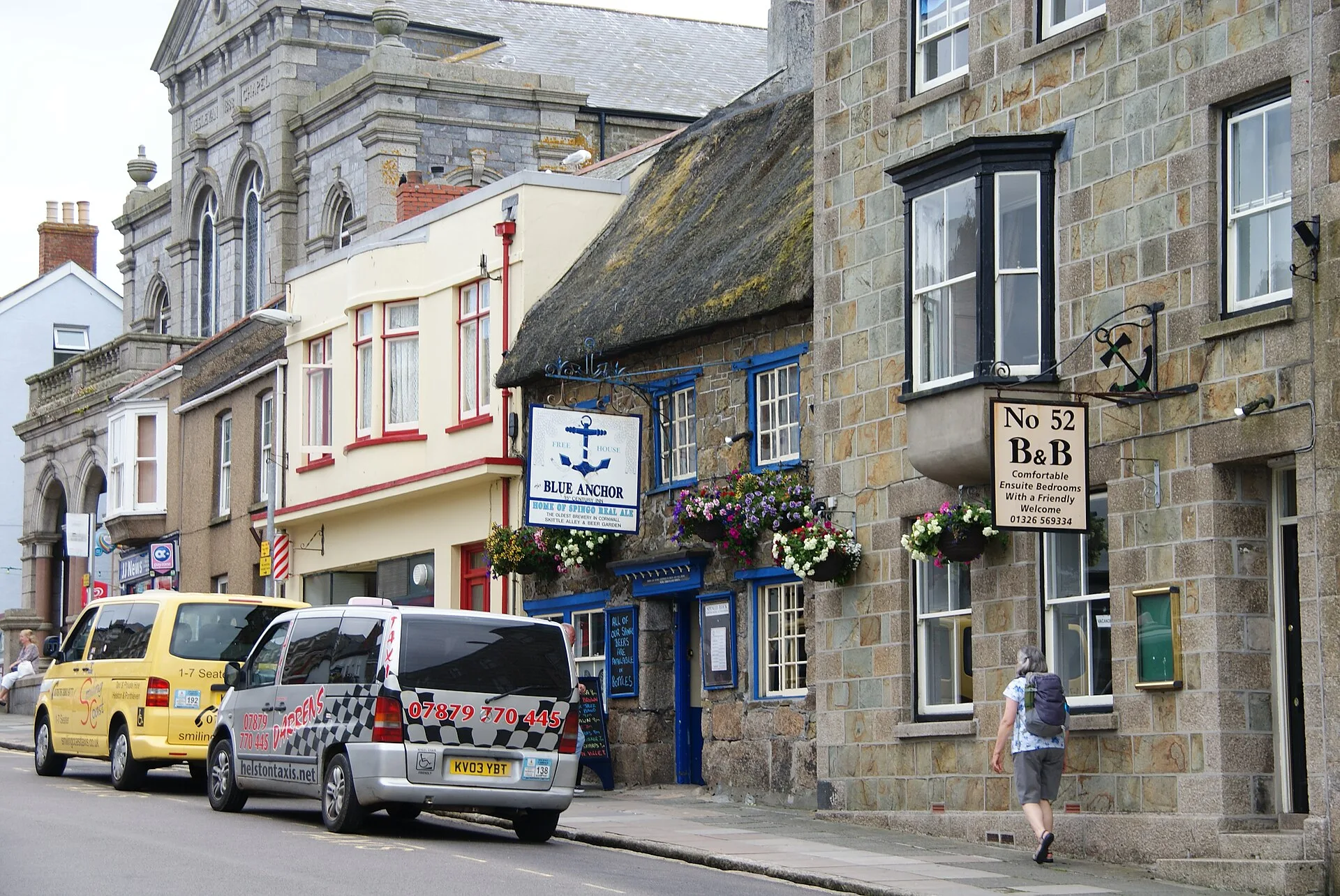 Stone pub building with a hanging sign beside a town street
