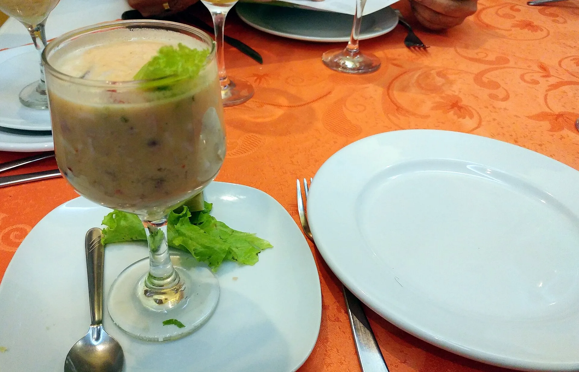 Glass of leche de tigre with a garnish on a restaurant table