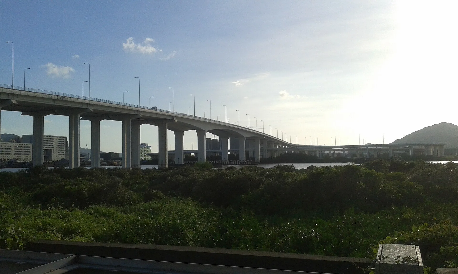 Long curved road bridge crossing the water under a cloudy sky