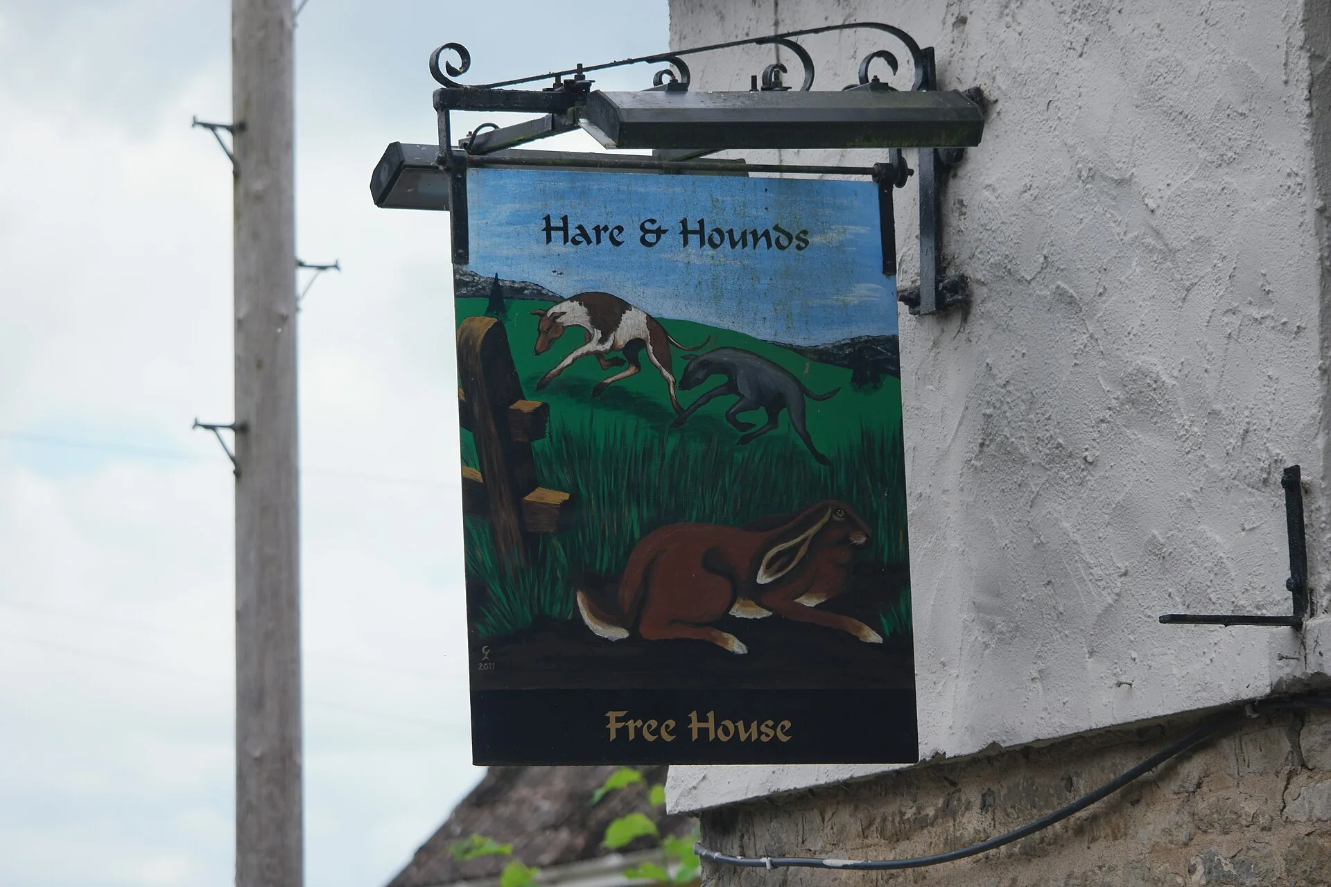 Hand-painted pub sign hanging from a black metal bracket