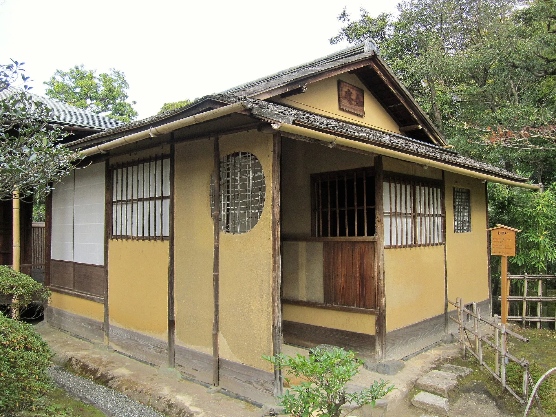 Small tea house with ochre plastered walls, latticed windows and a shingled roof