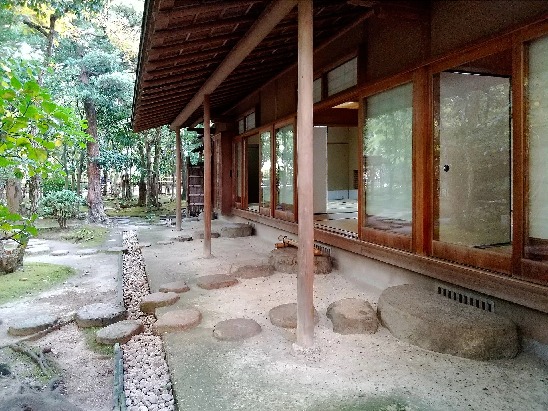 Stepping stones and gravel beneath deep eaves beside a tea house veranda