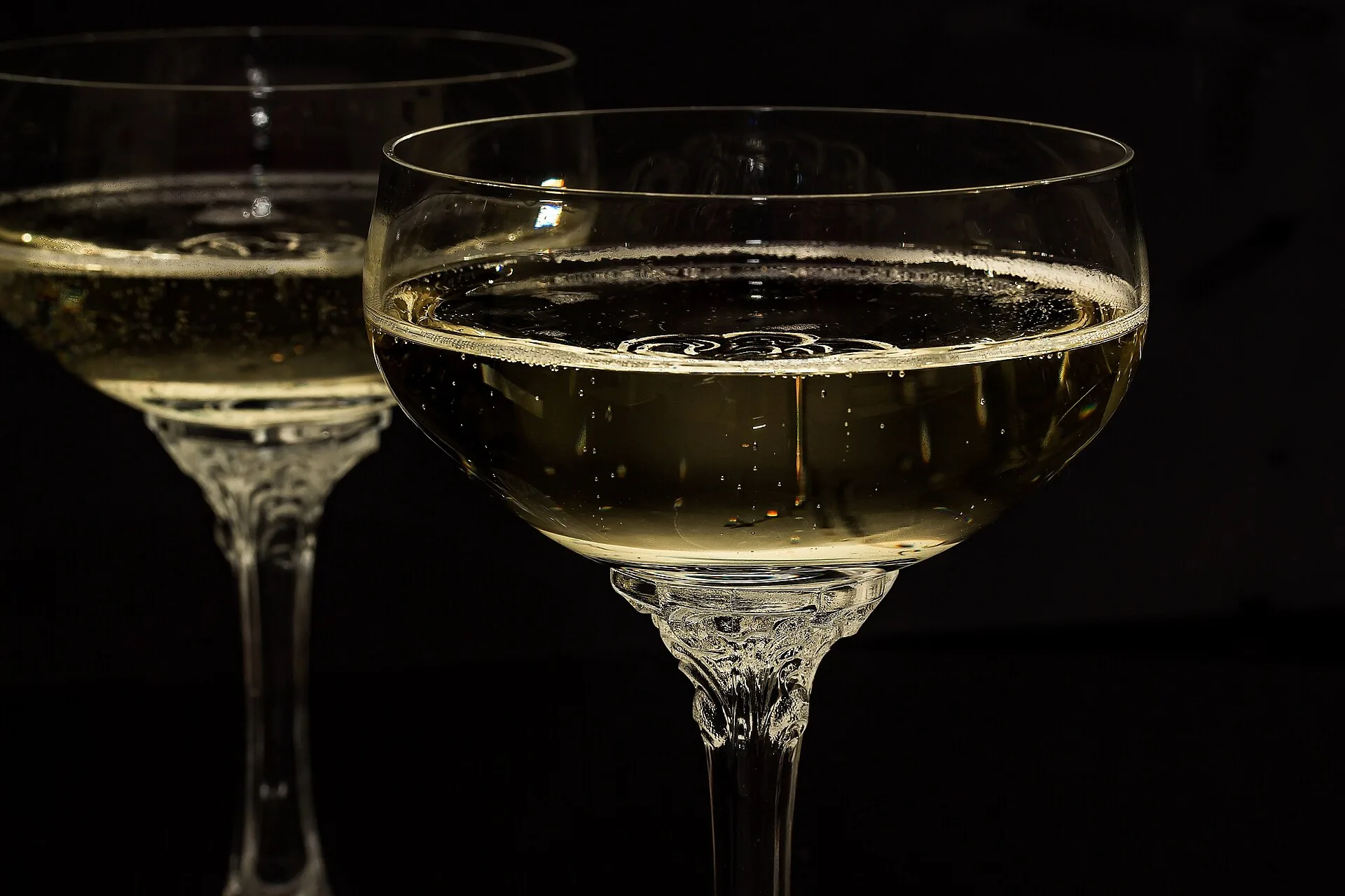 Two champagne glasses filled with sparkling wine against a dark background