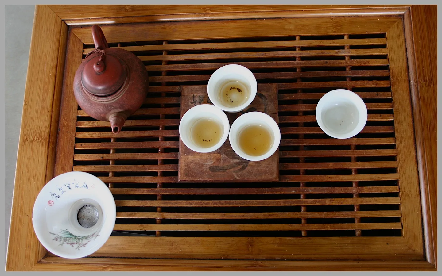 Small clay teapot and tiny cups on a wooden tea tray