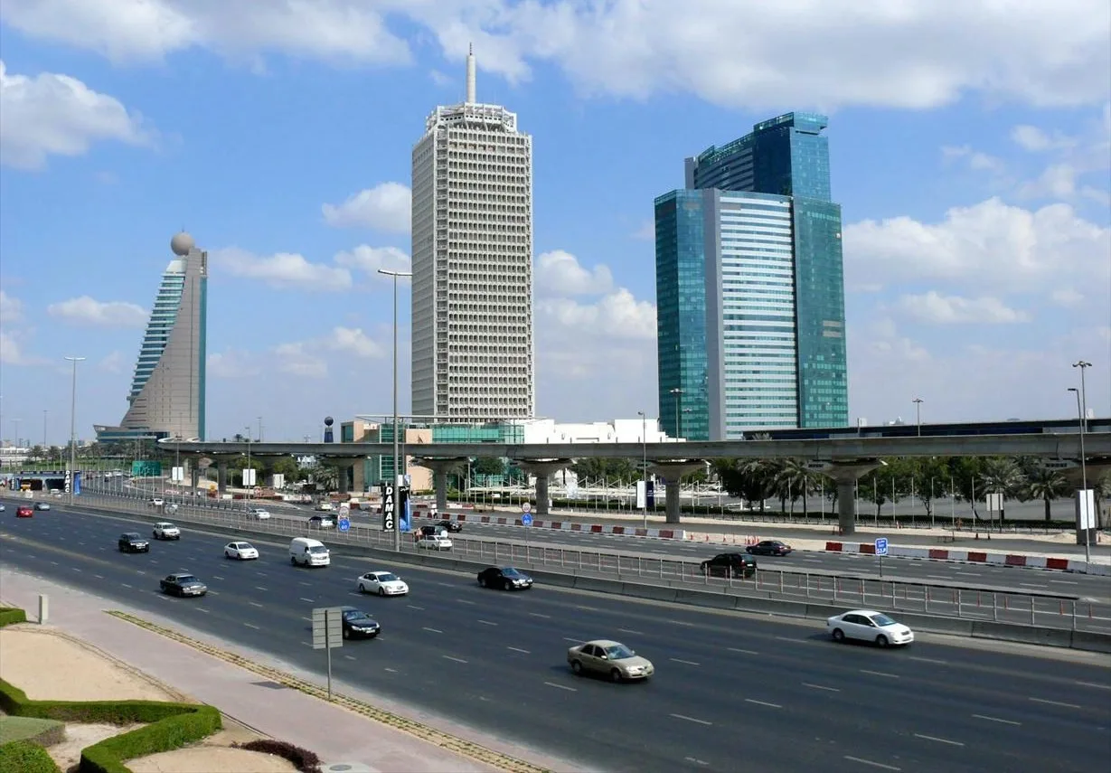 Three high-rise towers including the Dubai World Trade Centre beside a highway
