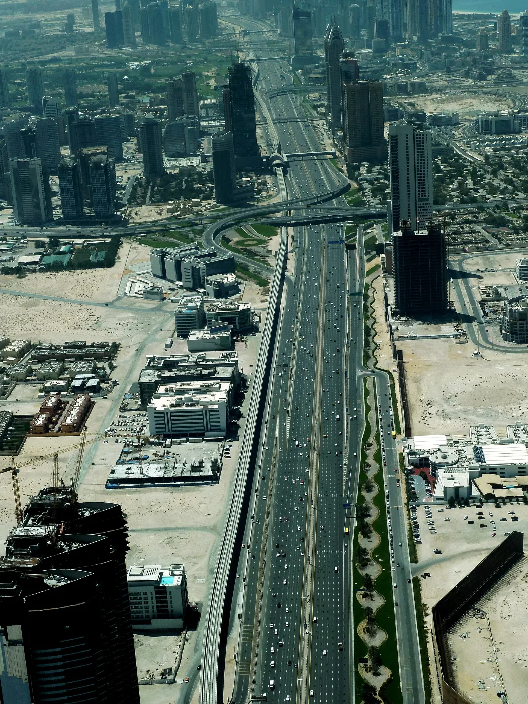 Aerial view of a wide multi-lane highway with an elevated metro line alongside