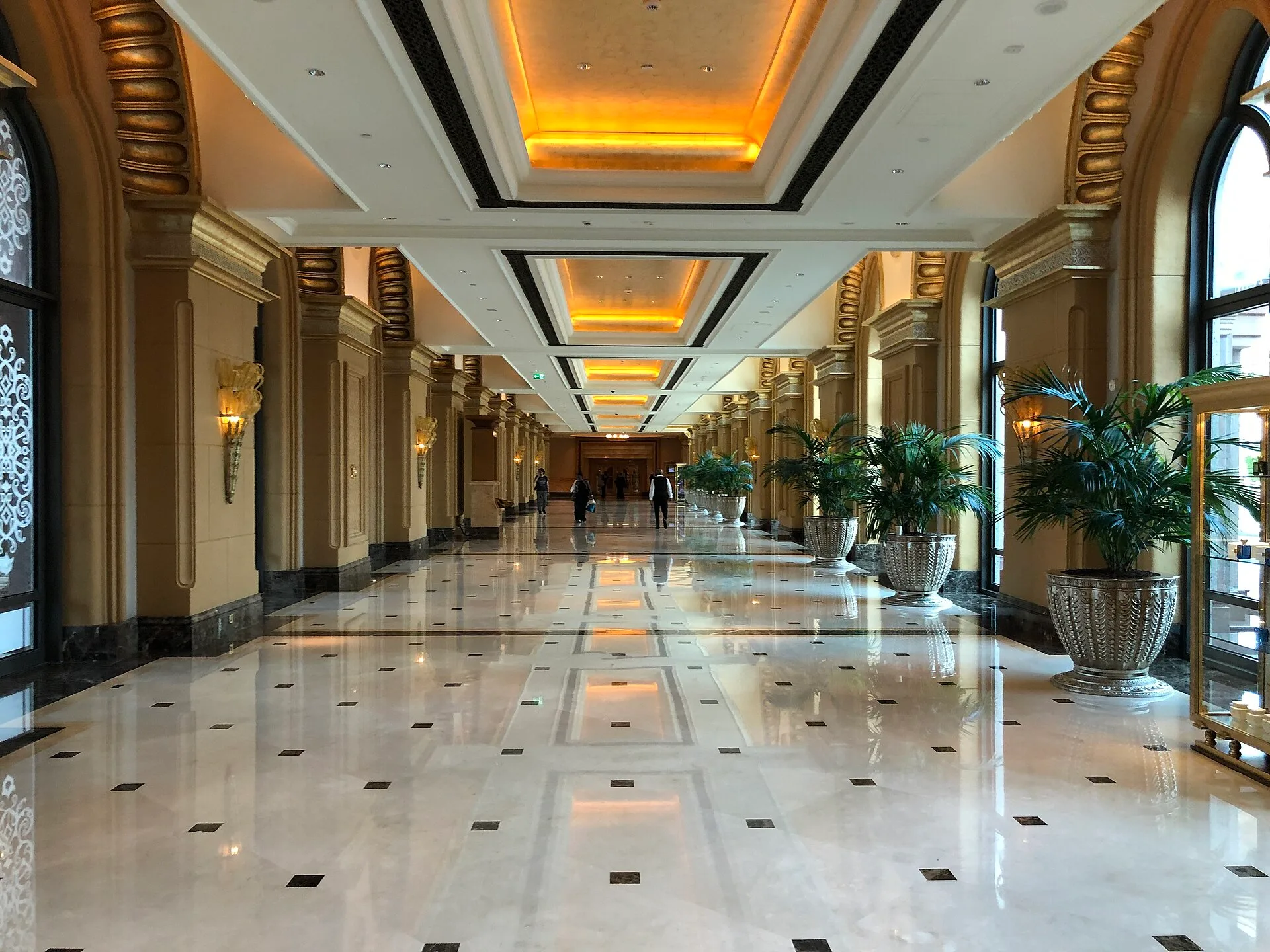 Long marble corridor with arched windows and golden ceiling lights