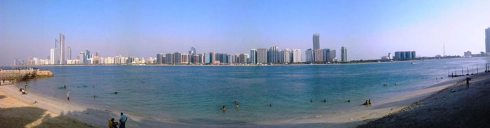 Panoramic view of a curved beach and waterfront skyline along the Abu Dhabi Corniche