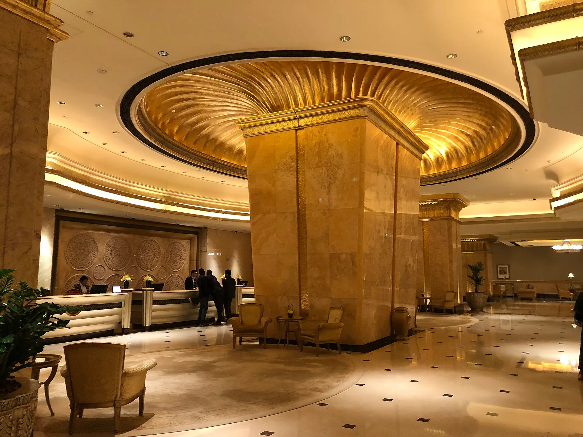 Gilded domed ceiling above a marble-floored hall with golden columns