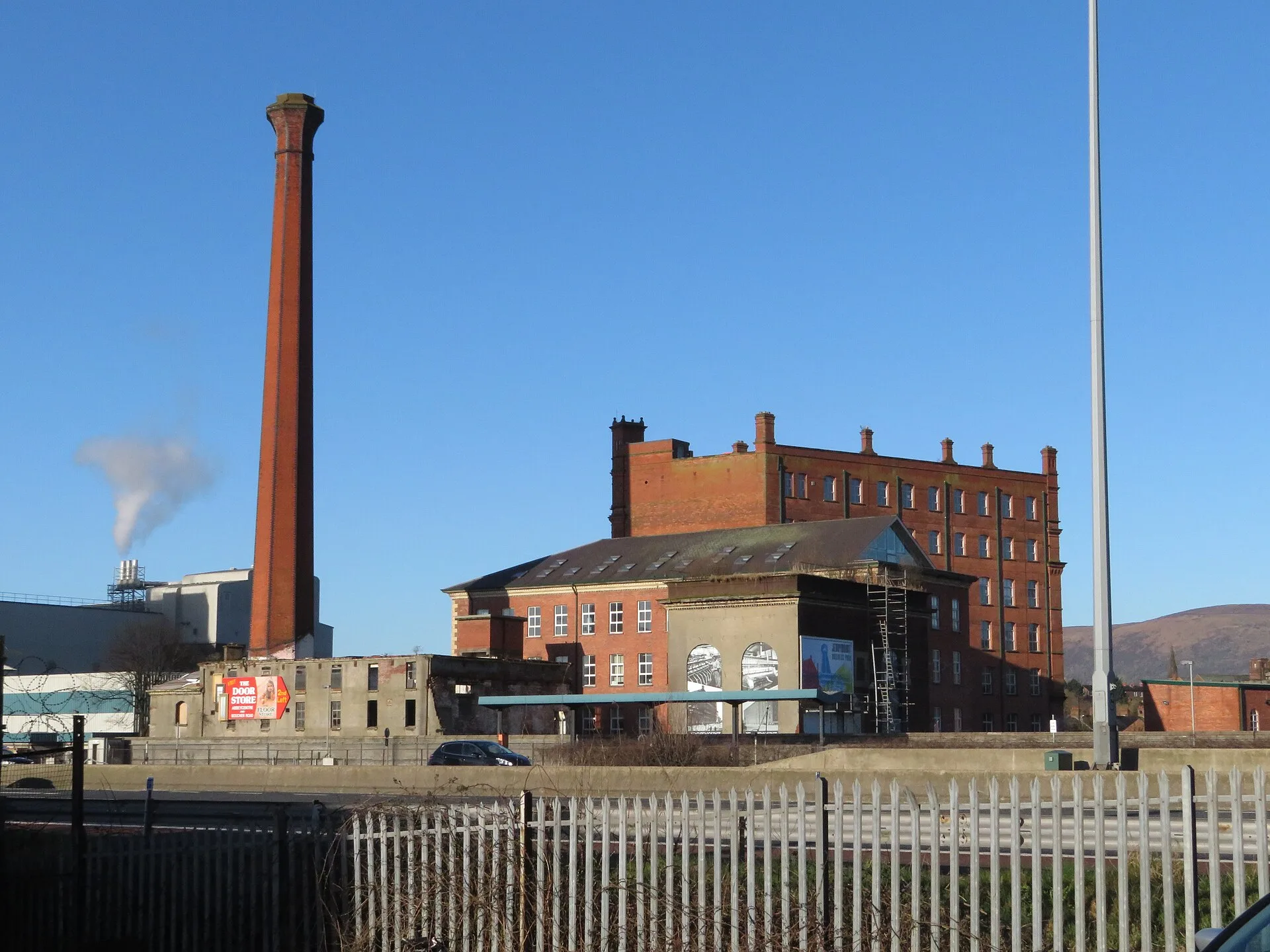 Red brick former linen mill with a tall chimney in Belfast