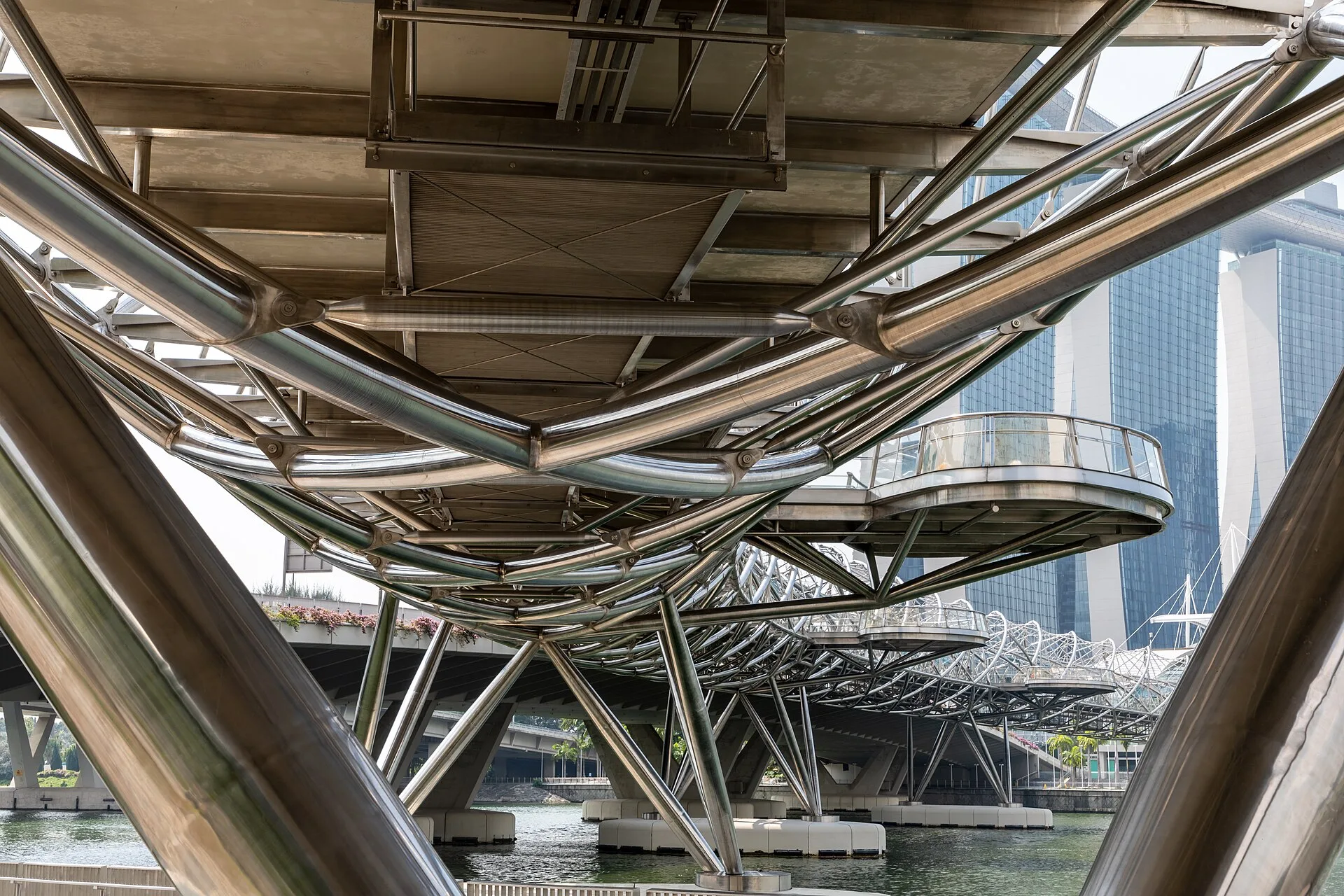 Curving steel bridge with interlocking spiral tubes over a walkway