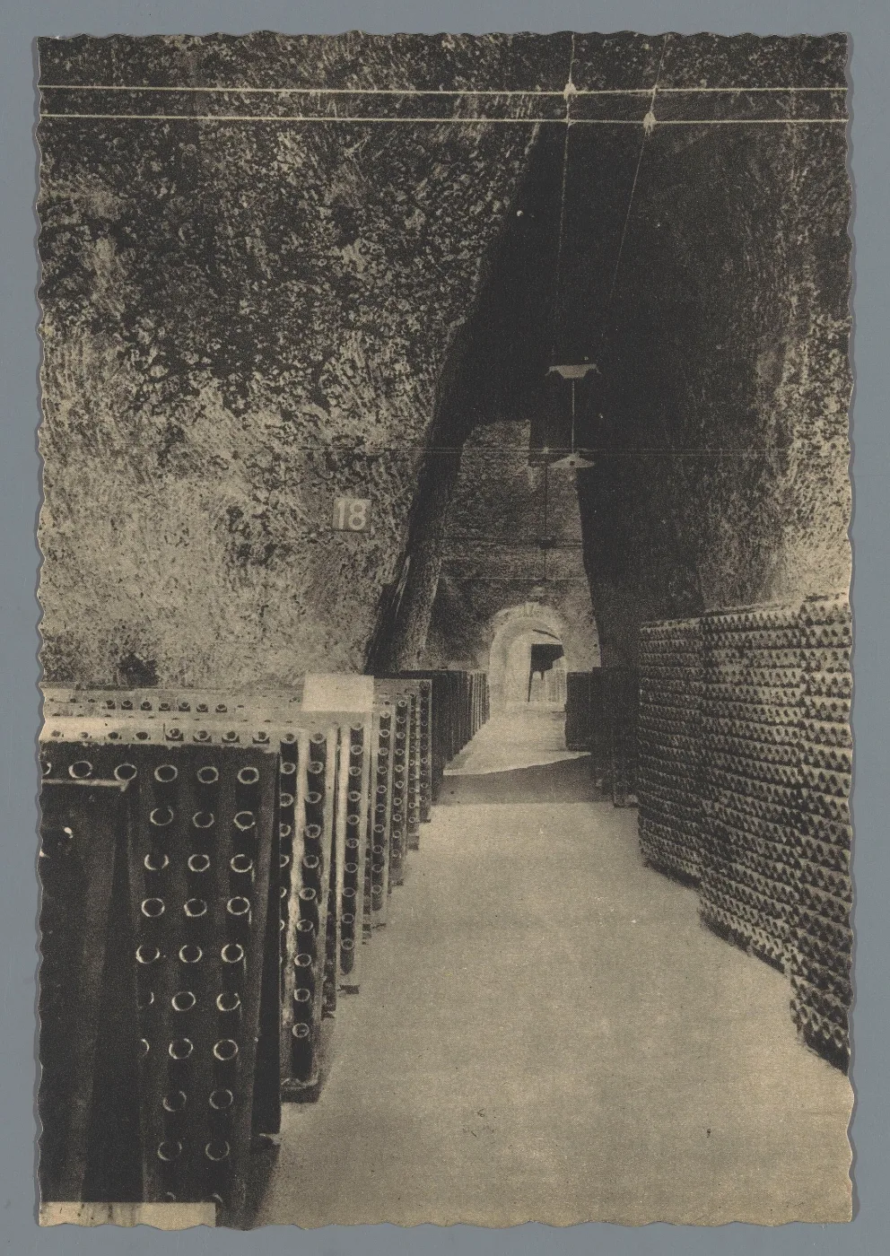 Historic photograph of a long chalk cellar passage lined with racked bottles