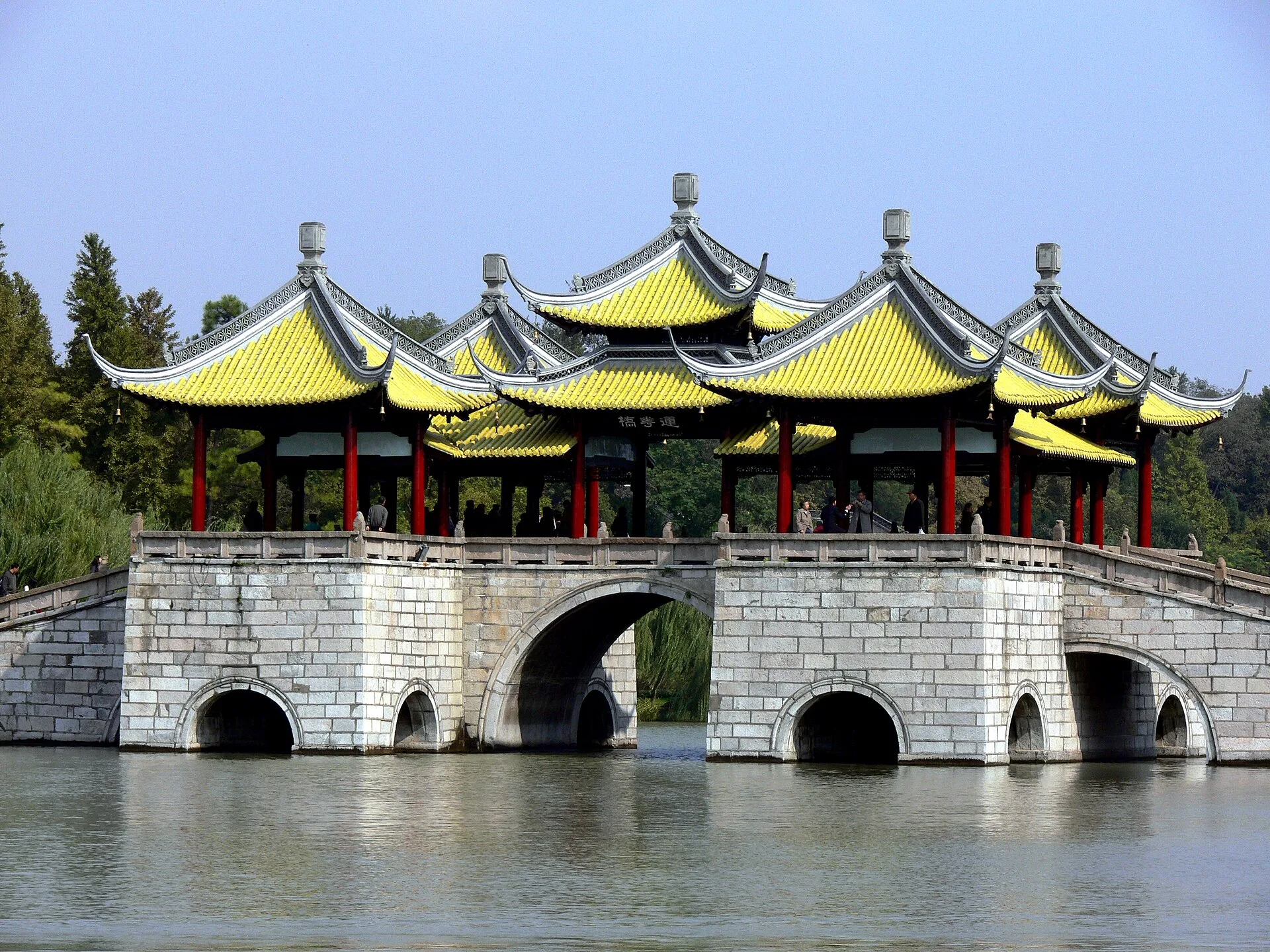 Stone bridge topped with five yellow-roofed pavilions over a lake