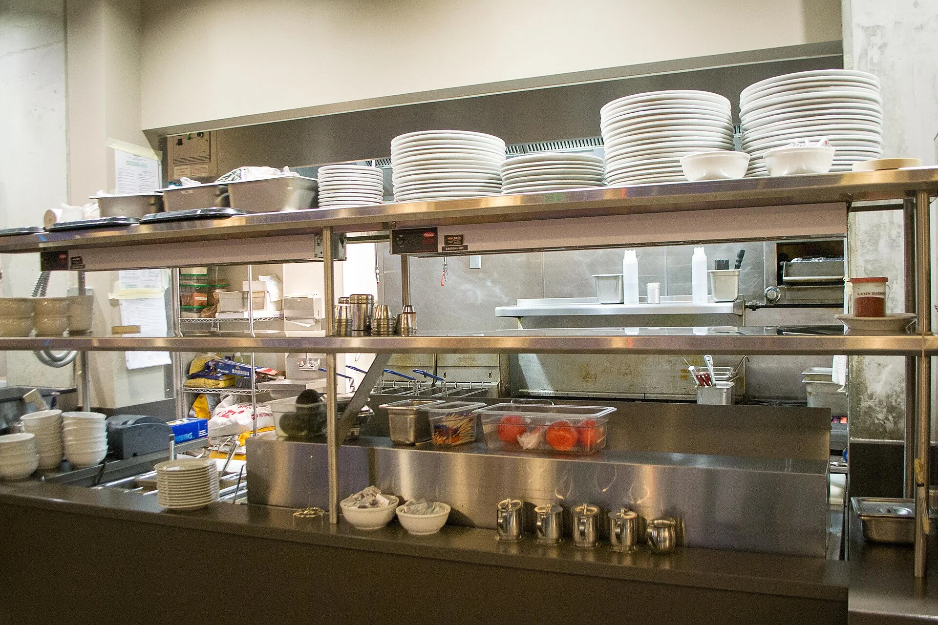 Stainless steel pass shelf stacked with plates between a diner kitchen and counter