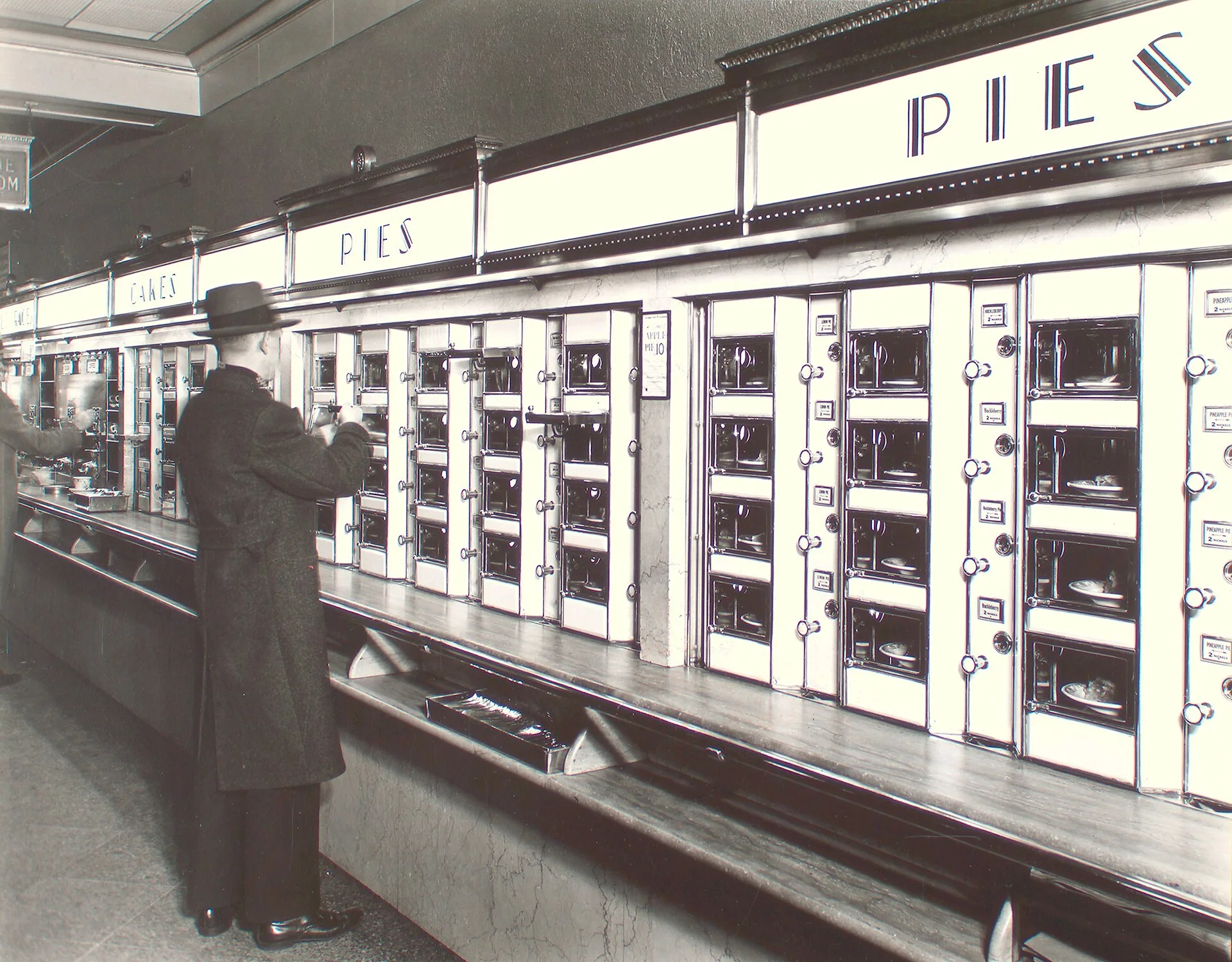 Man taking pie from a wall of glass-fronted Automat compartments