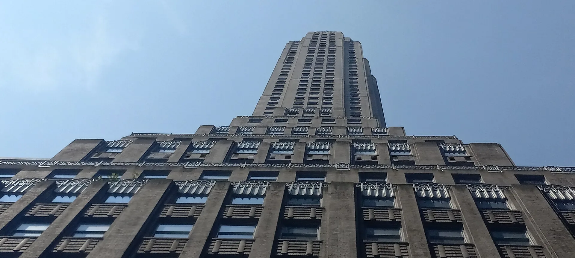 Looking up a stepped brick skyscraper narrowing to a slender top