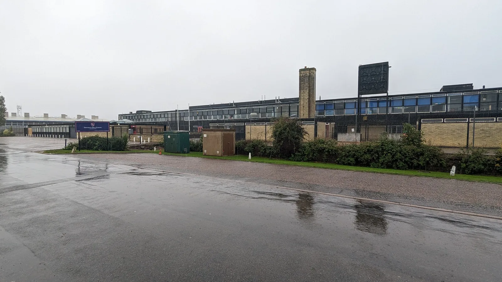 Low steel and glass school buildings with a water tower behind