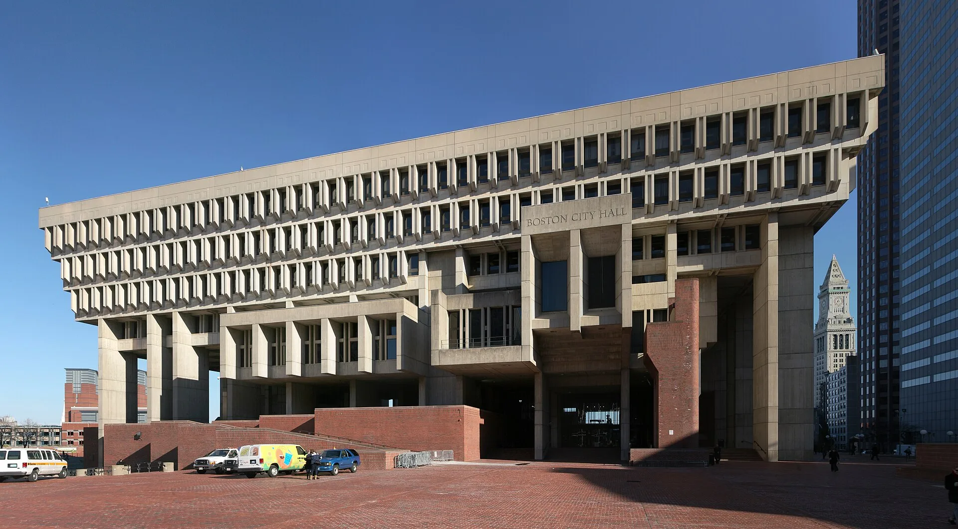 Concrete city hall with projecting upper floors above a brick plaza