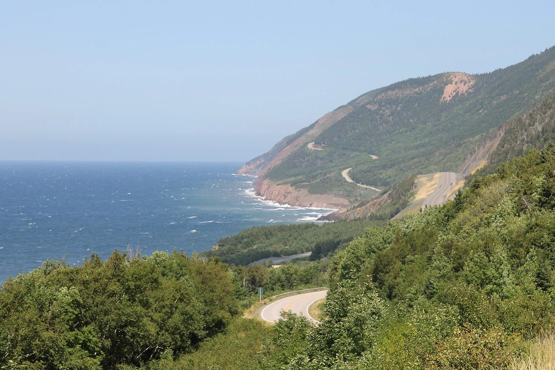Green coastal hills dropping to the sea along a winding road