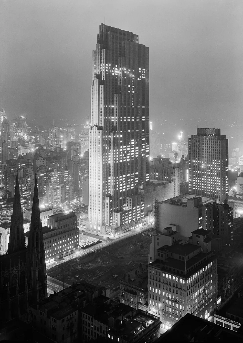 Night view of a tall stepped tower lit above lower buildings