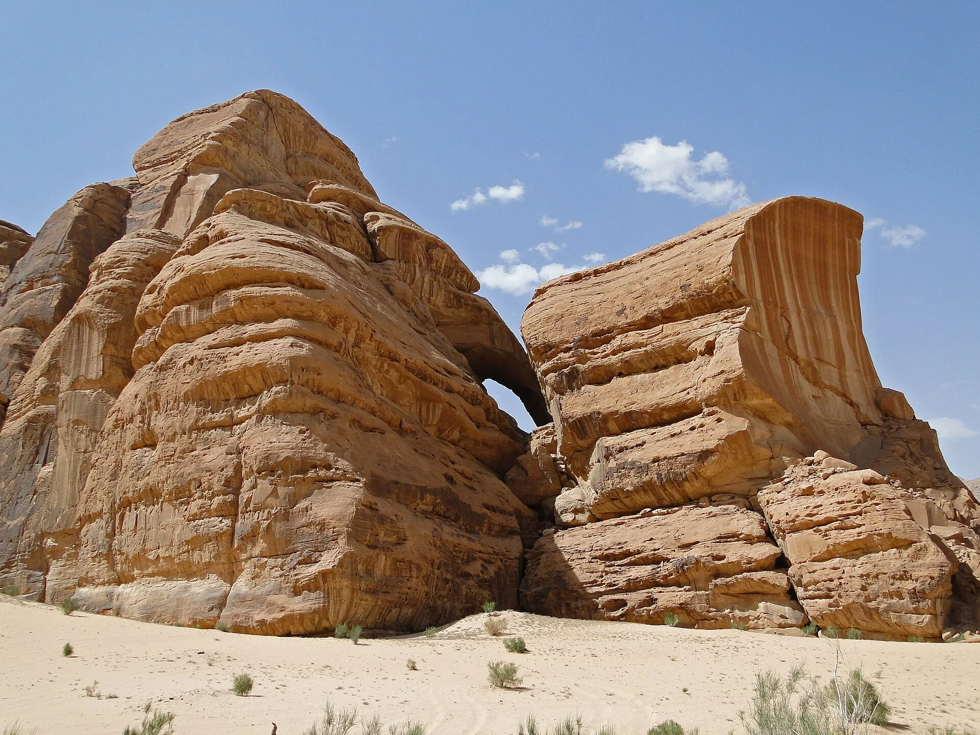 Weathered sandstone outcrop with a natural rock arch against a blue sky