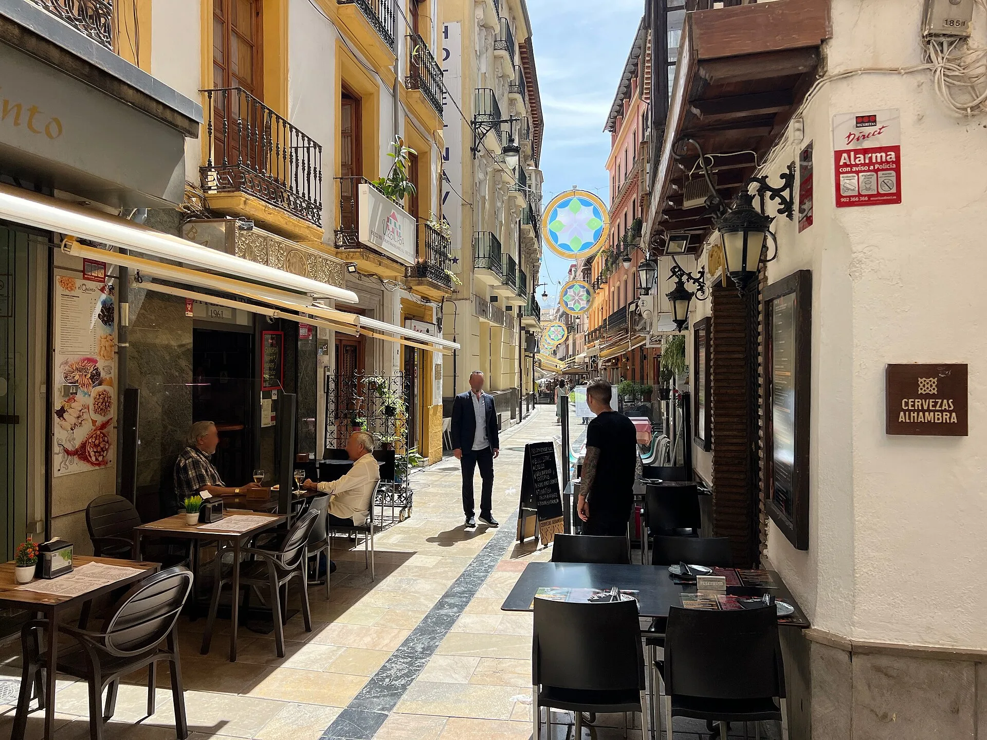 Narrow pedestrian street lined with bars and restaurant terraces