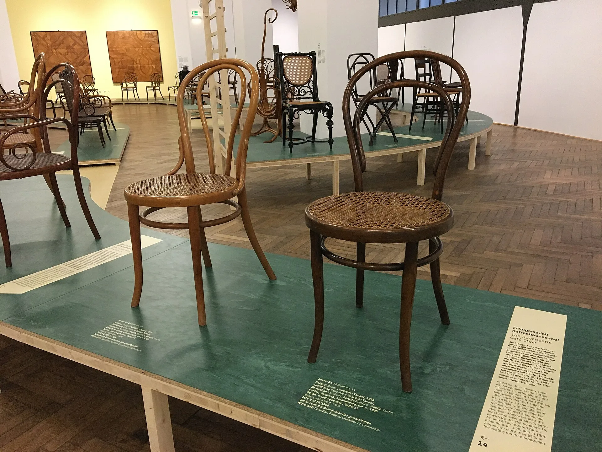 Several bentwood chairs displayed on a low platform in a gallery