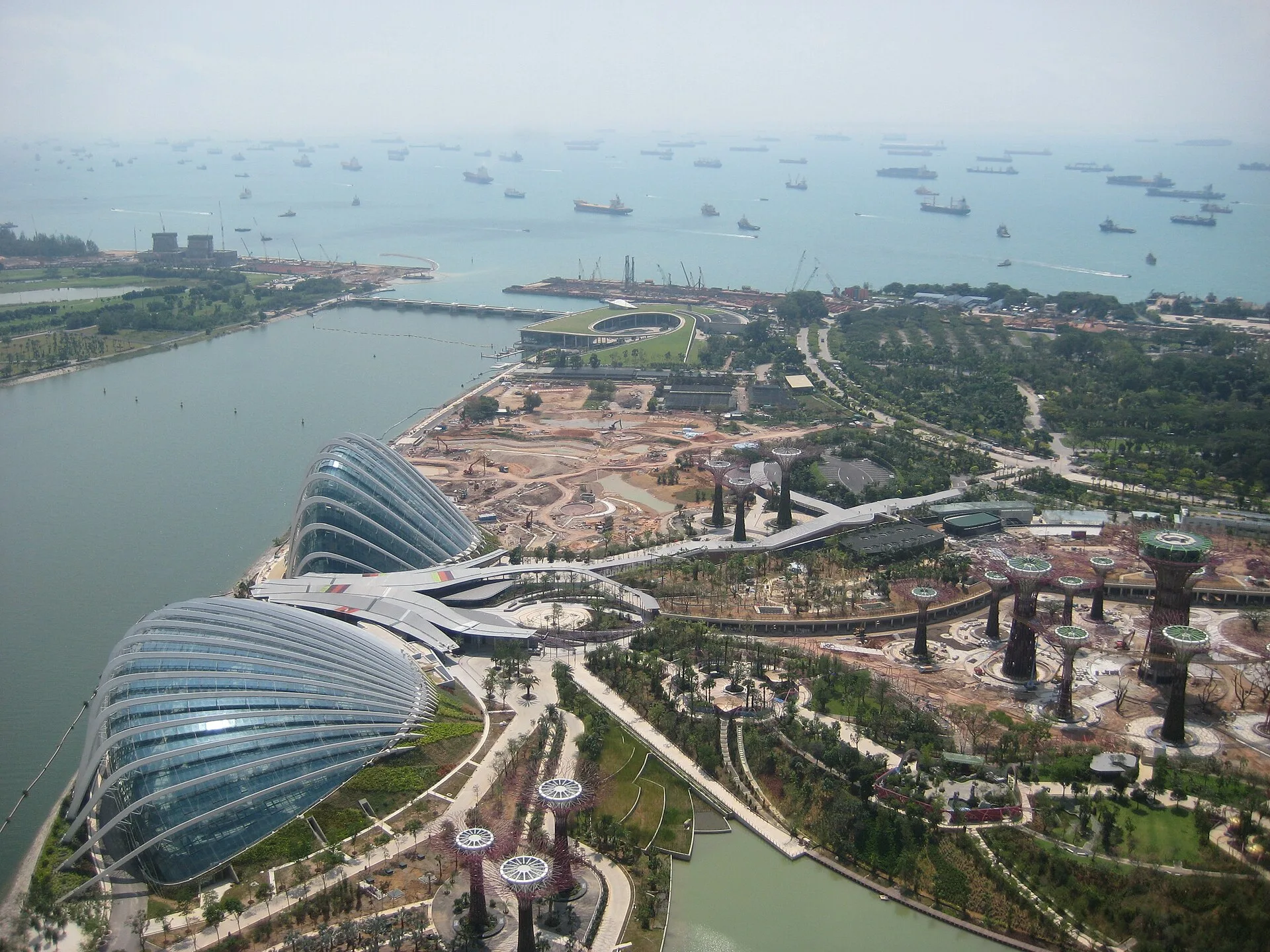 Aerial view of two glass domes and bare landscaped ground beside a bay