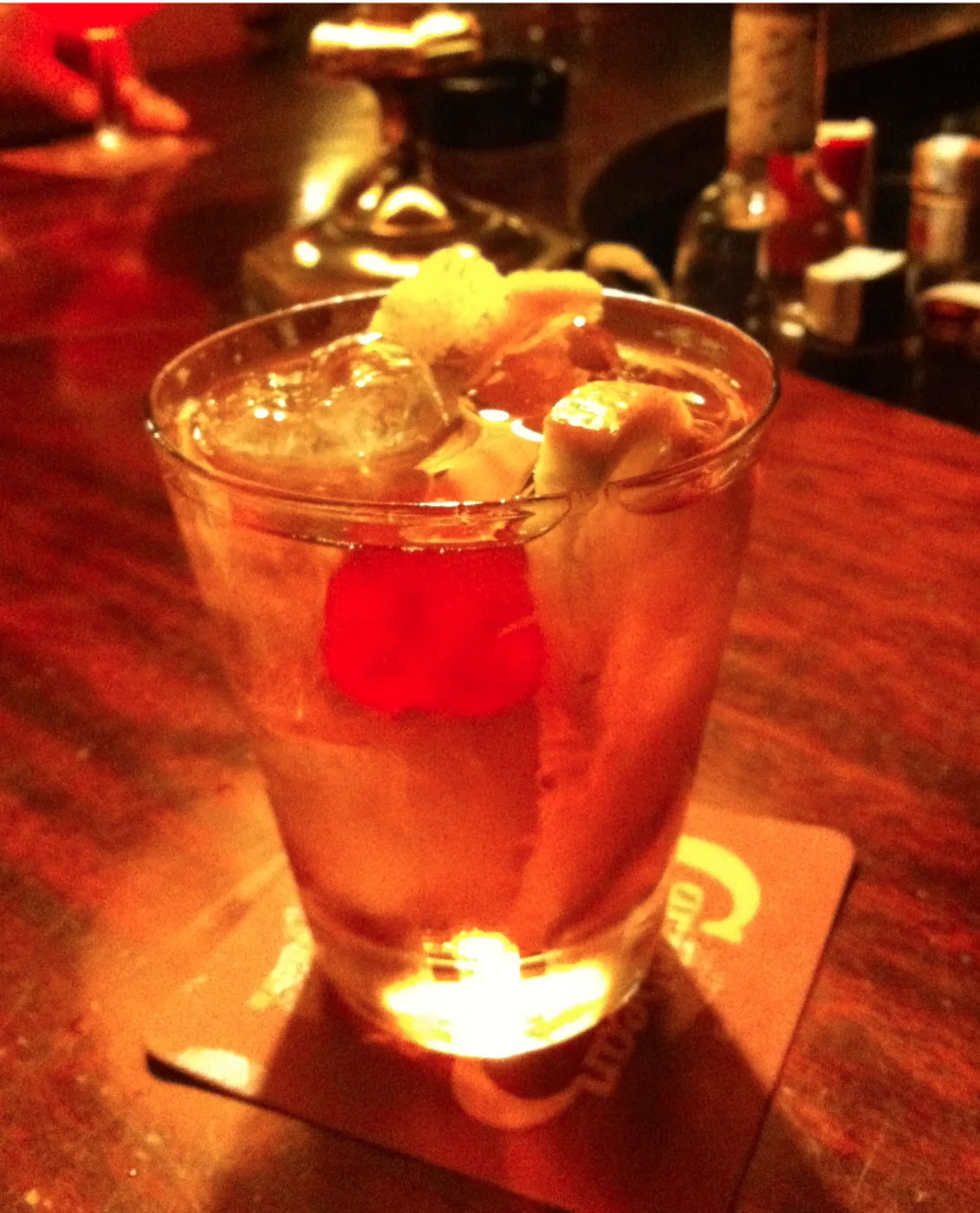 Old Fashioned with fruit and ice in a tumbler on a candlelit bar