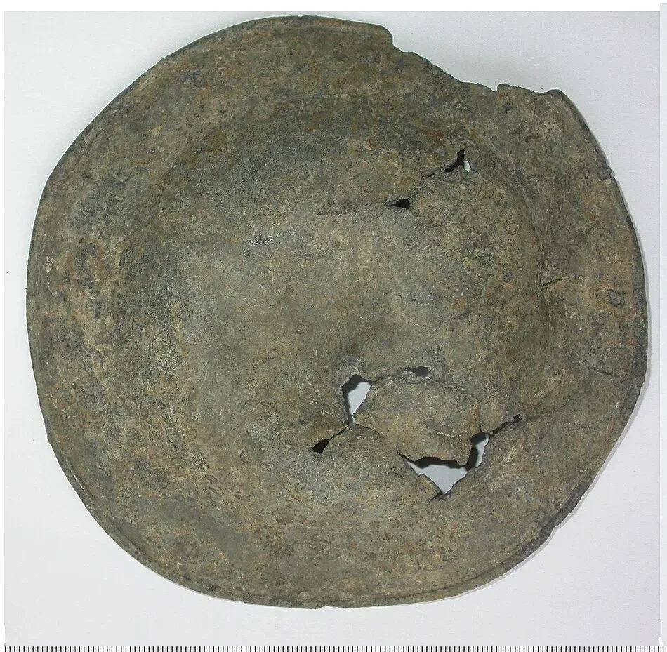 Worn grey pewter dish with a narrow rim and small holes