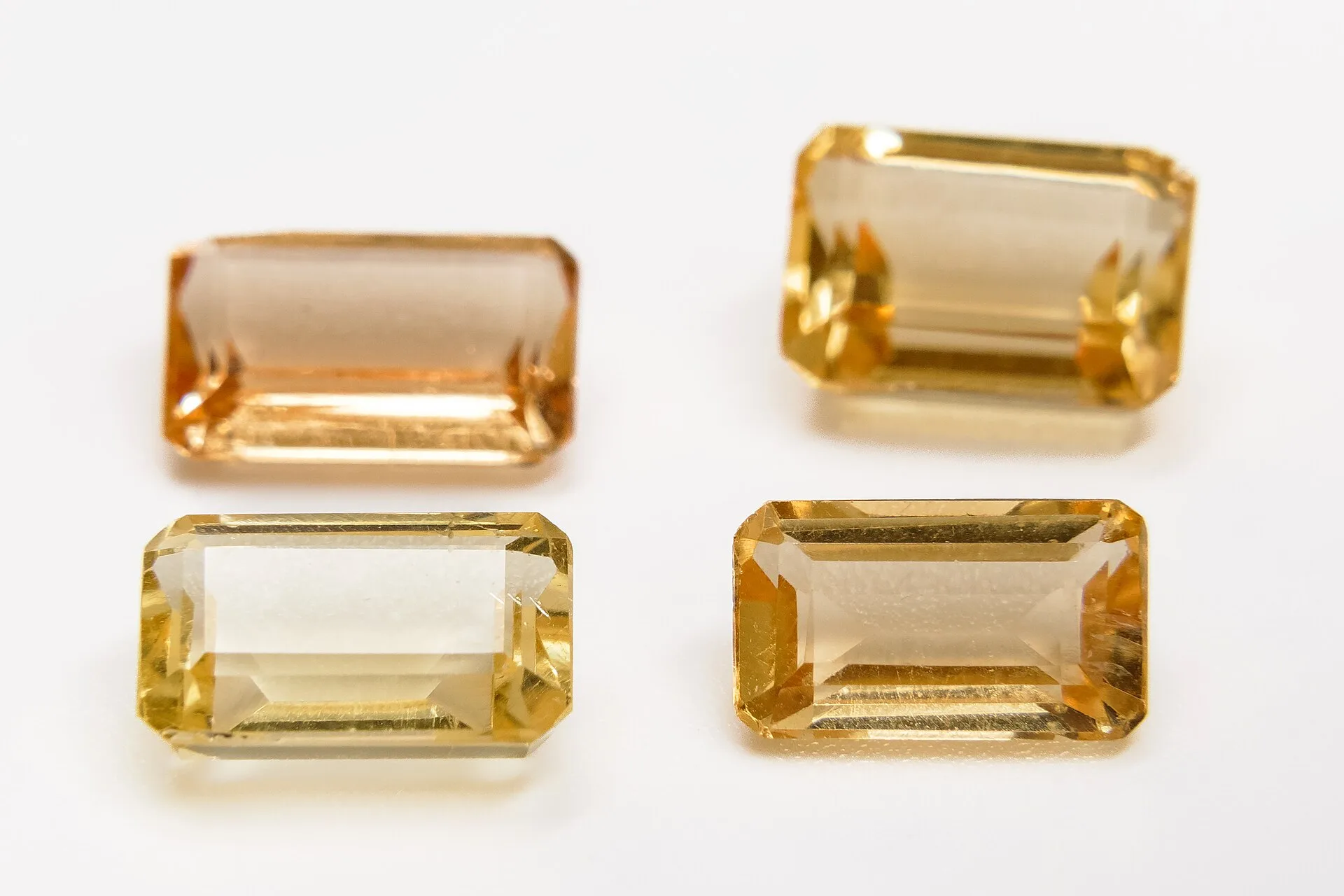 Four rectangular step-cut golden gemstones on a white surface