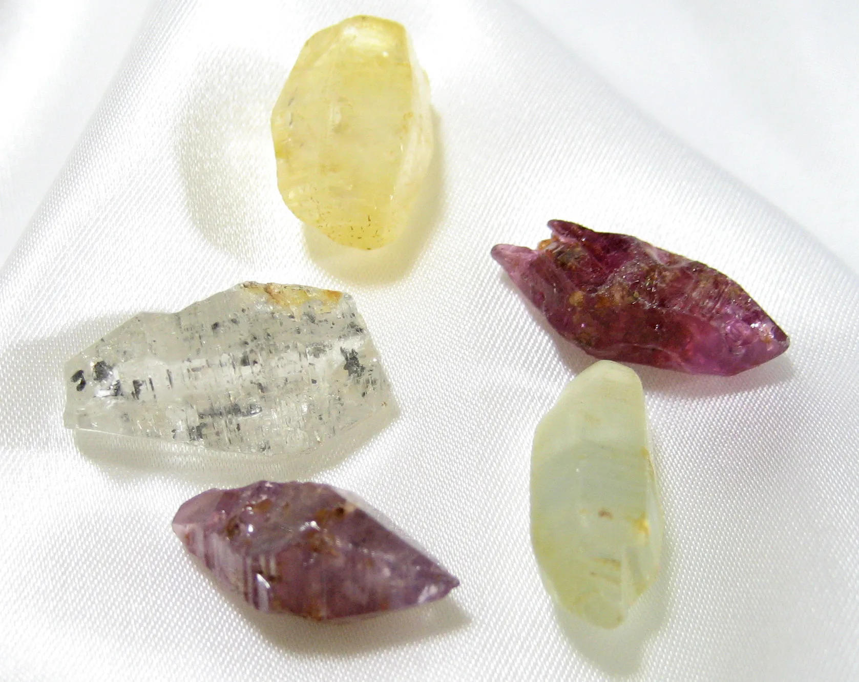 Five rough corundum crystals in pink, purple, yellow and clear tones