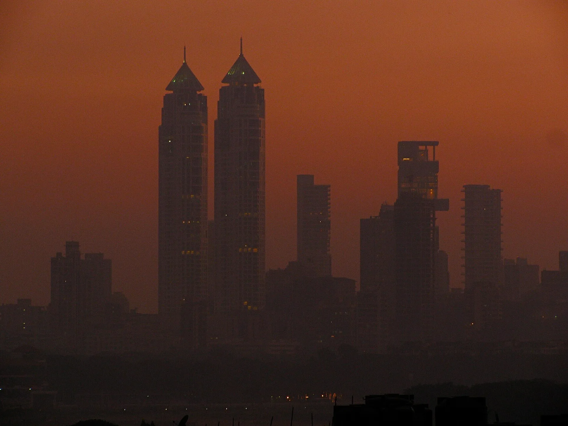 Silhouette of twin pointed towers against an orange evening sky