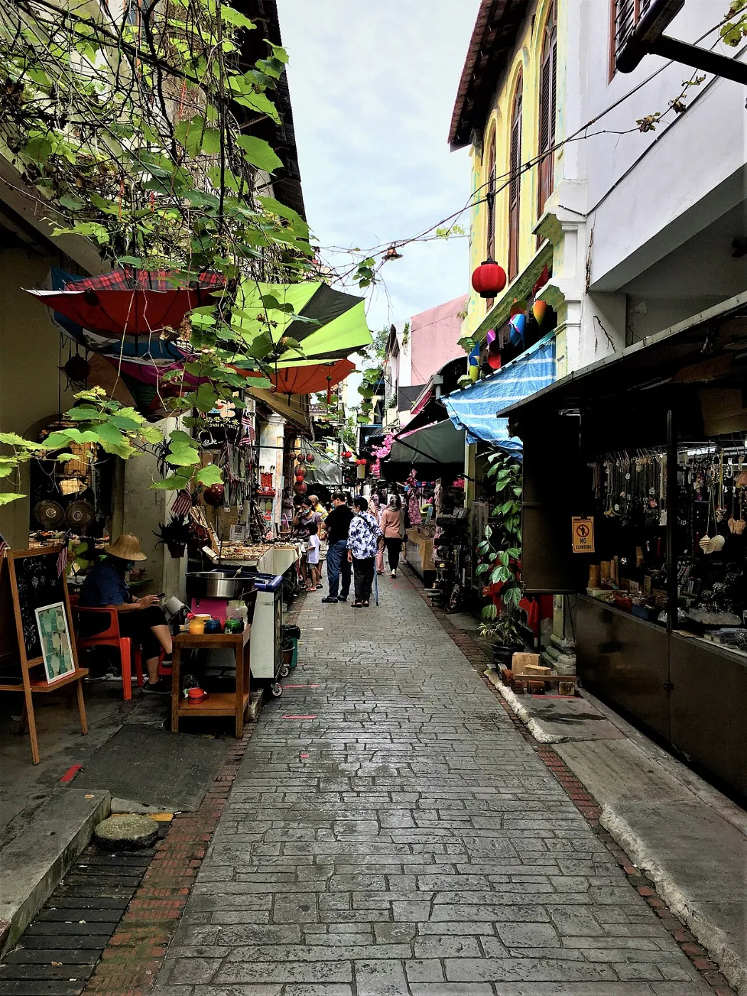 Narrow lane lined with old shophouses, stalls and hanging lanterns