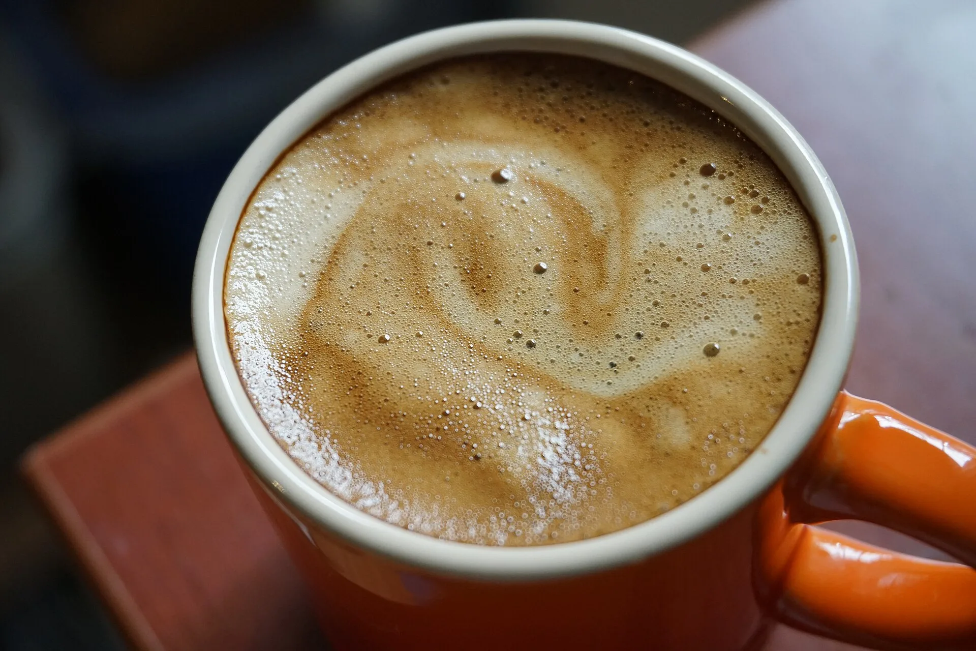Swirled golden crema on top of coffee in an orange cup